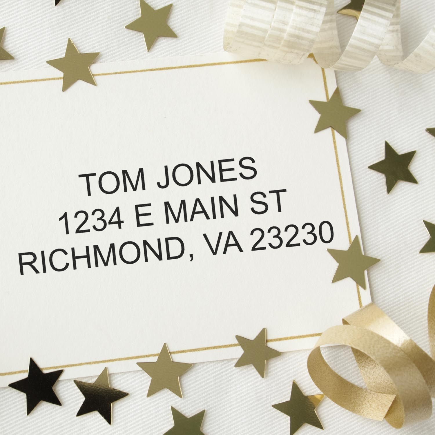 Create a Custom Rubber Stamp for Your Home or Business Feature Post Image: A custom stamp with an address on a card surrounded by gold stars and ribbons.