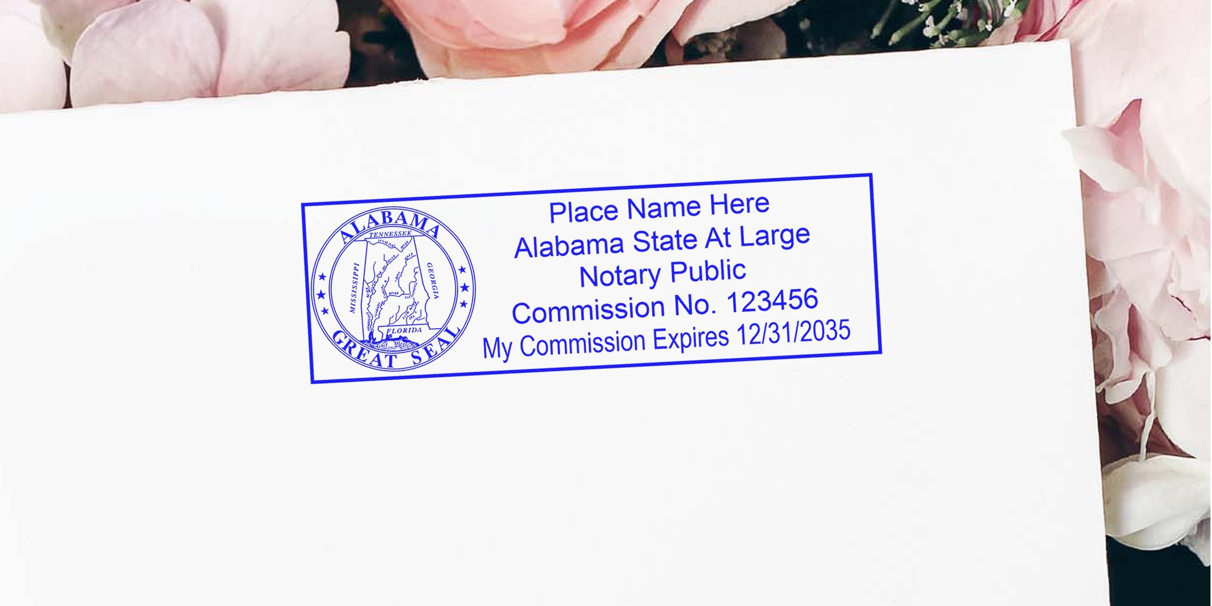 Blue Alabama notary public stamp on white envelope with pink flowers, featuring circular state seal and rectangular text block with name placeholder, commission number and expiration date.