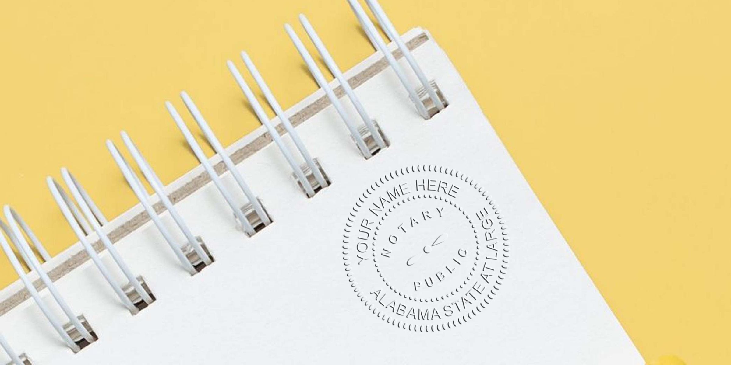 Close-up of white spiral-bound notebook corner on yellow background featuring an embossed Notary Public Alabama state seal on the paper