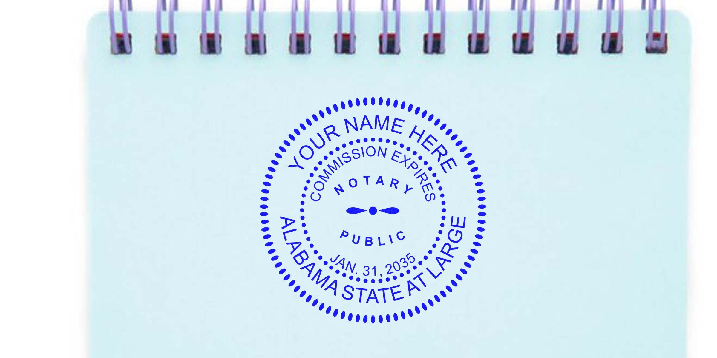 Blue circular Alabama notary public seal stamp reading "YOUR NAME HERE" and "Commission Expires Jan. 31, 2035" centered on a light blue spiral-bound notepad.