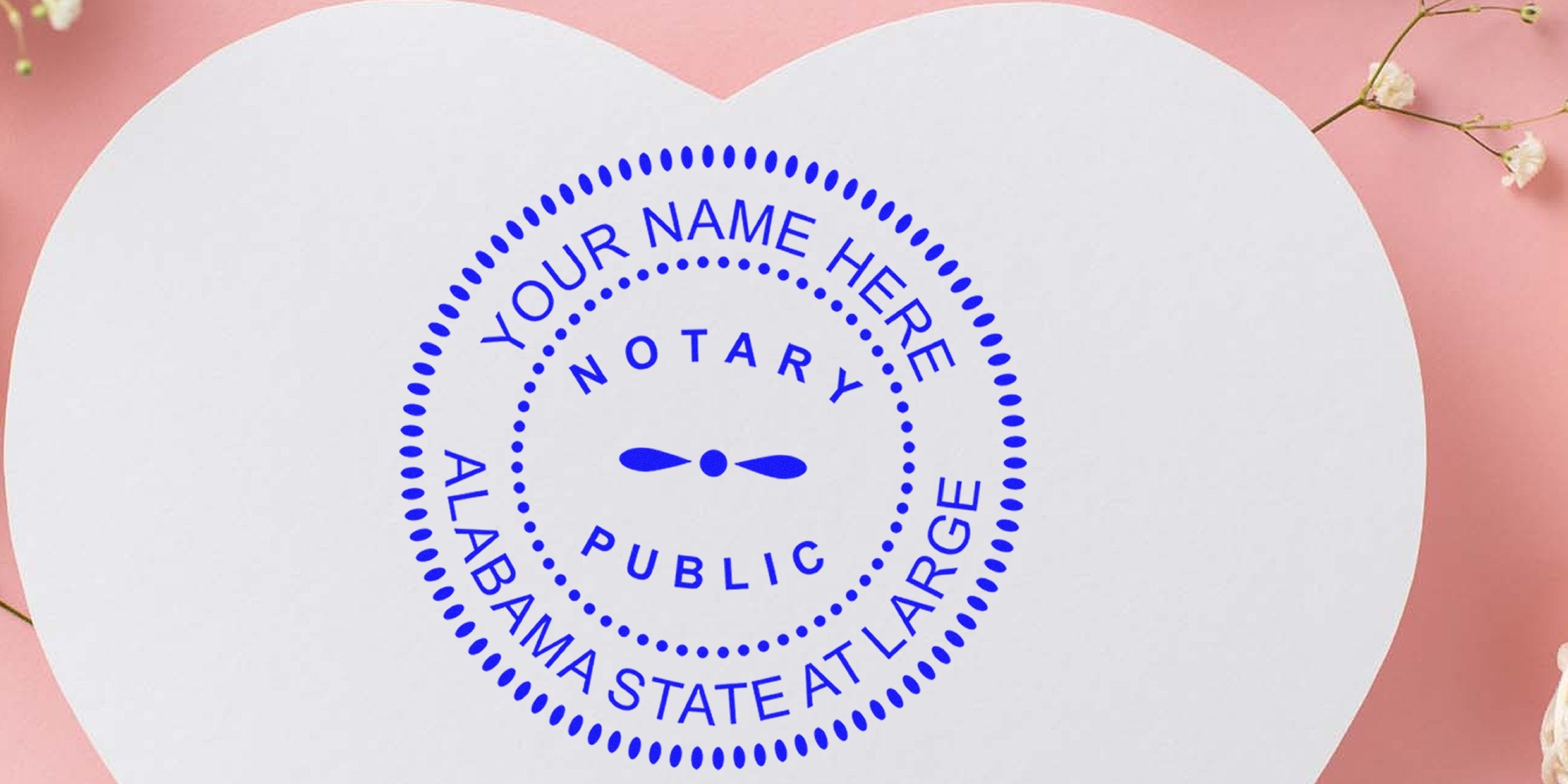 Blue circular notary public seal reading "Your Name Here, Notary Public, Alabama State At Large" centered on a white heart-shaped card against a pink background with small white flowers.