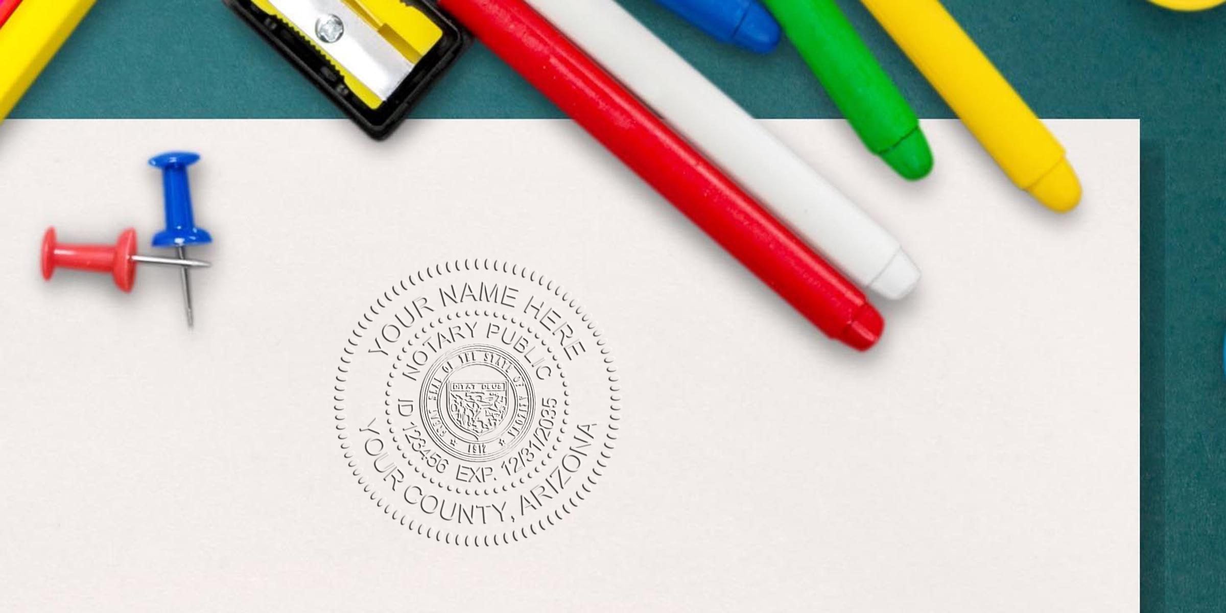 Top-down view of colorful markers, push pins and a sharpener on a teal background beside white paper embossed with a circular notary seal reading "Your Name Here, Notary Public, Your County, Arizona"