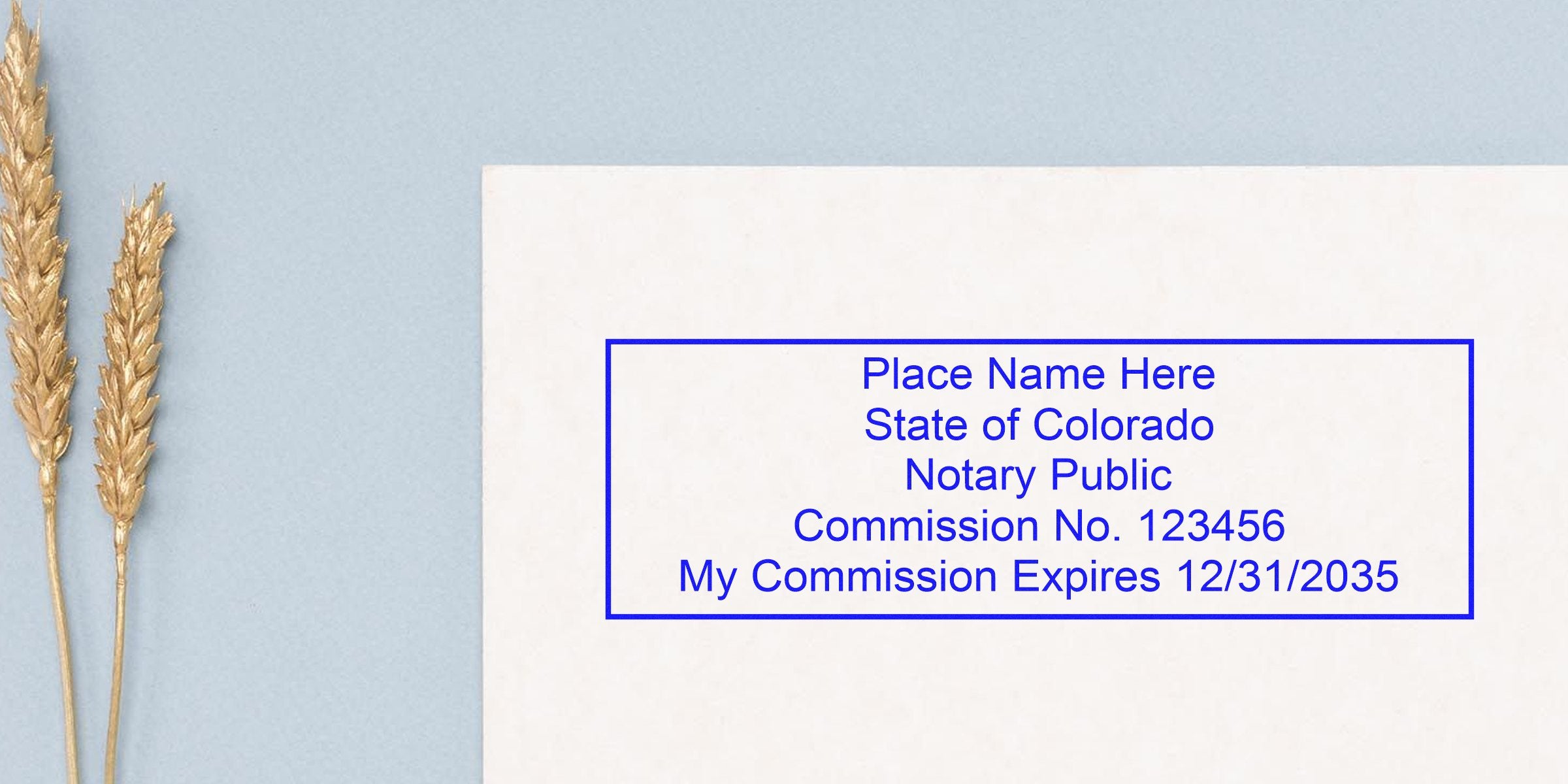 Blue notary stamp on white paper reading "Place Name Here, State of Colorado Notary Public, Commission No. 123456, My Commission Expires 12/31/2035" on a pale blue background with two decorative gold wheat stalks.