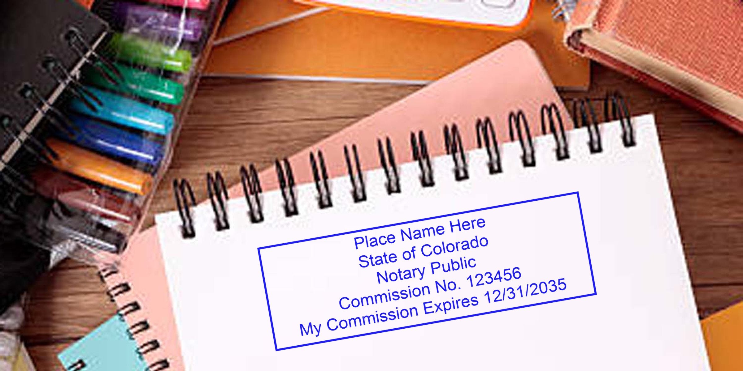 Top-view of spiral notebooks on a wooden desk with colorful gel pens and a blue-stamped notary sample reading "Notary Public, State of Colorado."