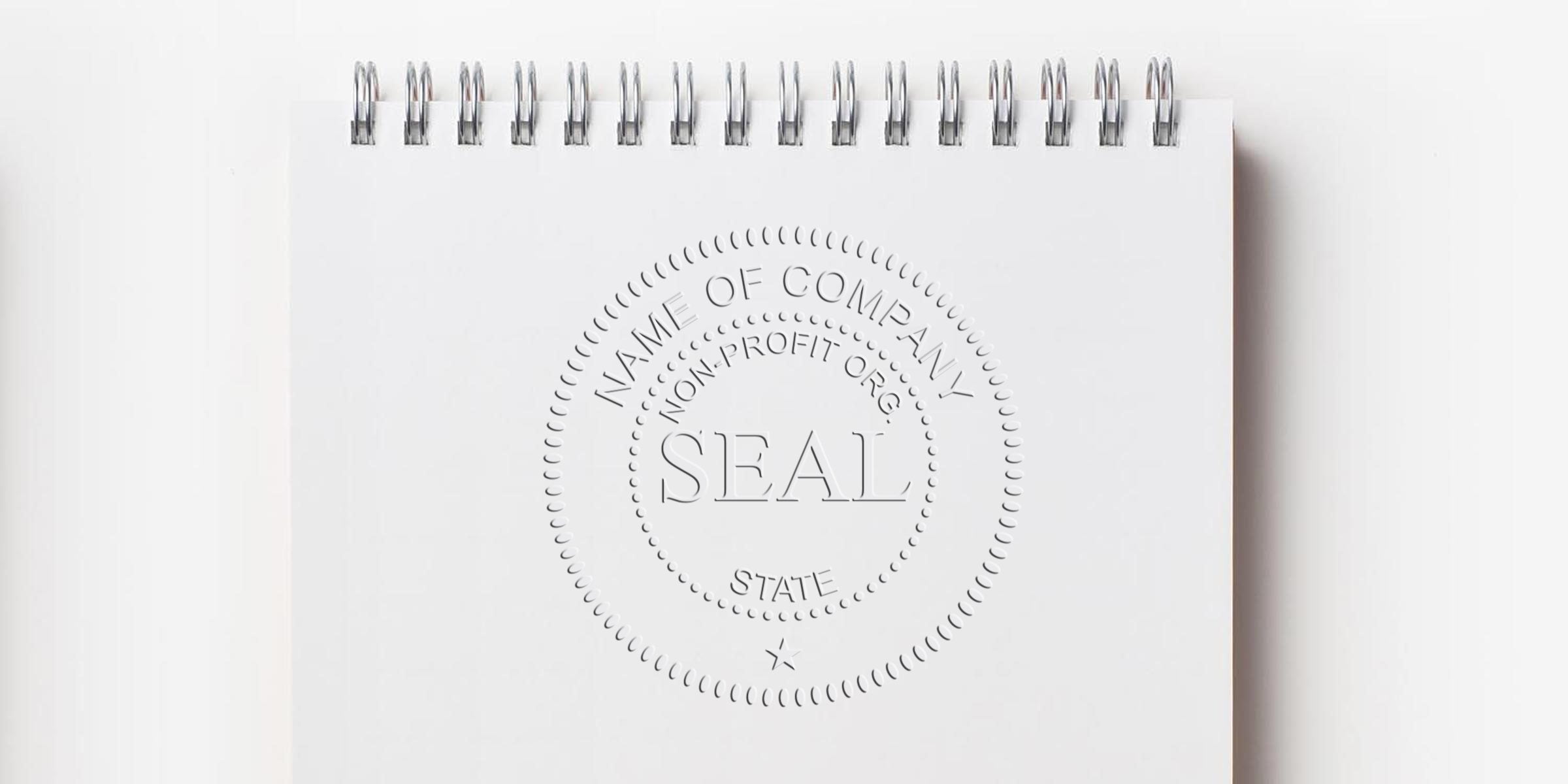 Embossed circular seal on a white spiral-bound notebook page, with the word SEAL at the center.