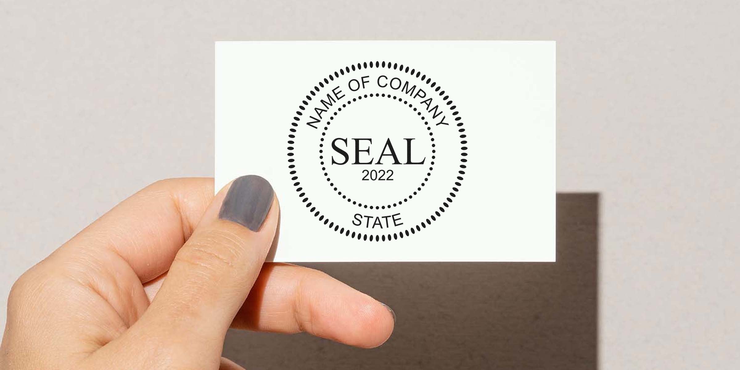 White card held by a hand featuring a circular seal that reads “NAME OF COMPANY SEAL 2022.”