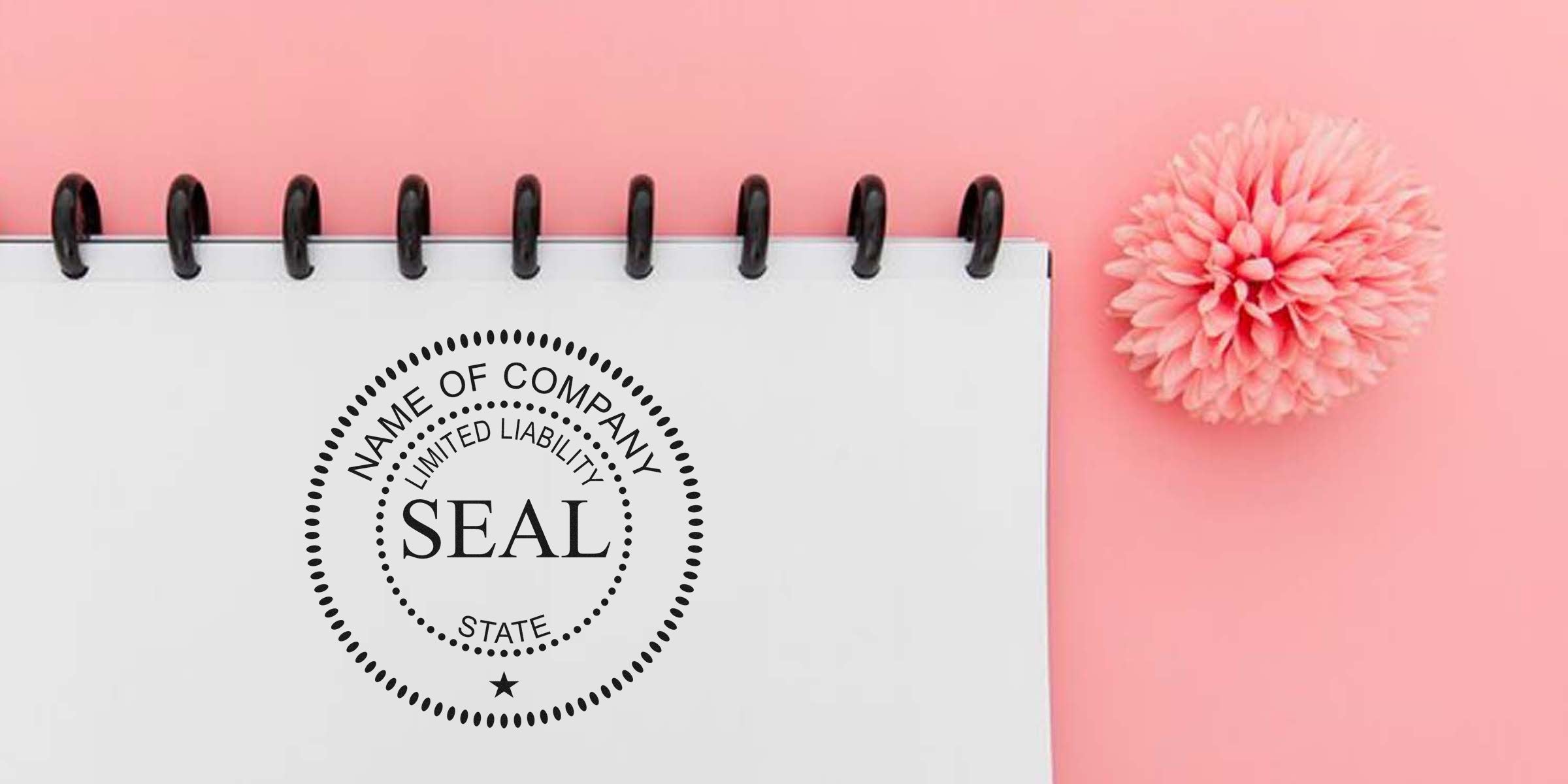 Circular company seal stamp on a spiral notebook page with a pink background and a pink flower.