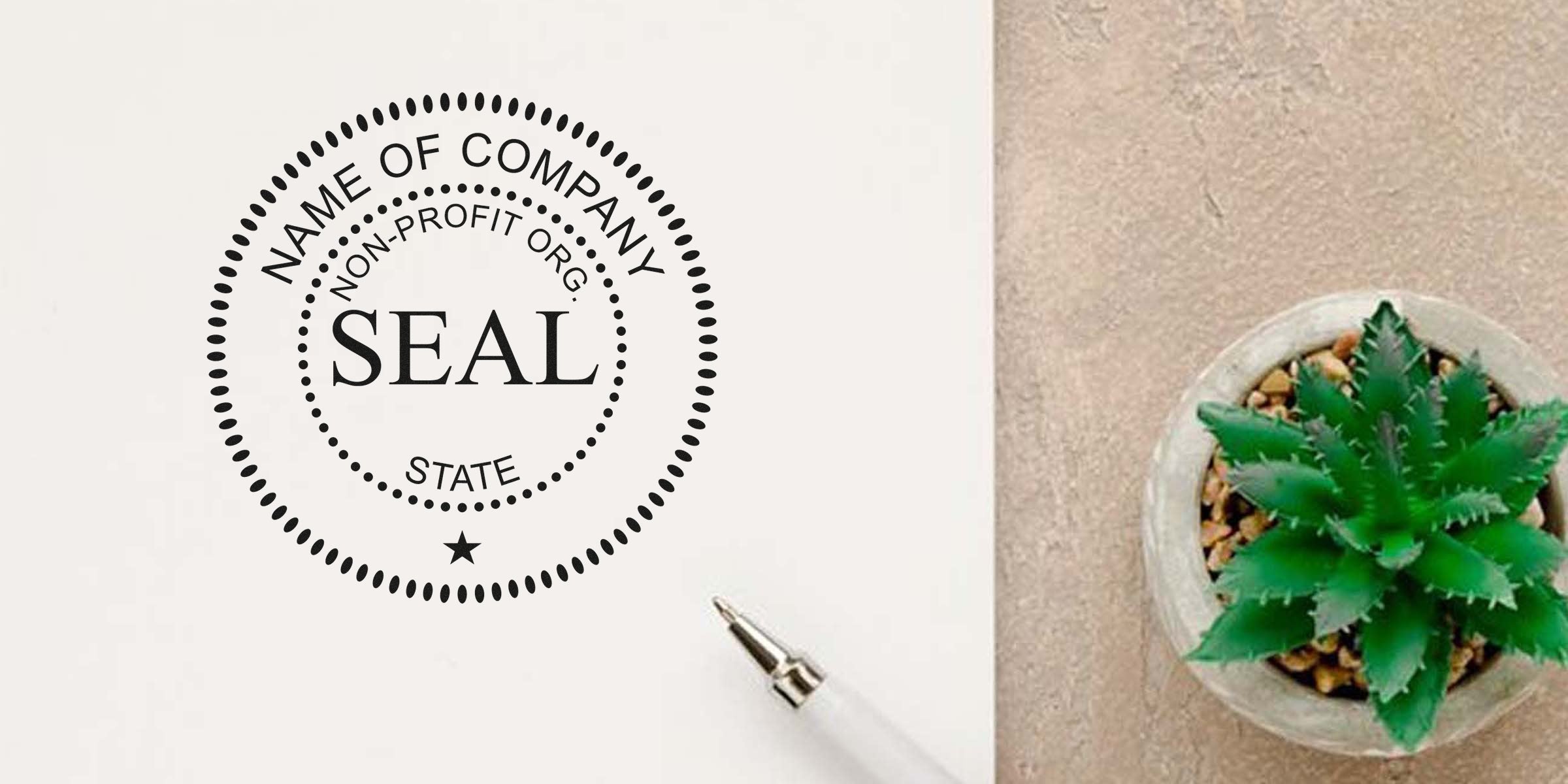 Seal stamp on white paper with a pen nearby and a potted succulent on the right.