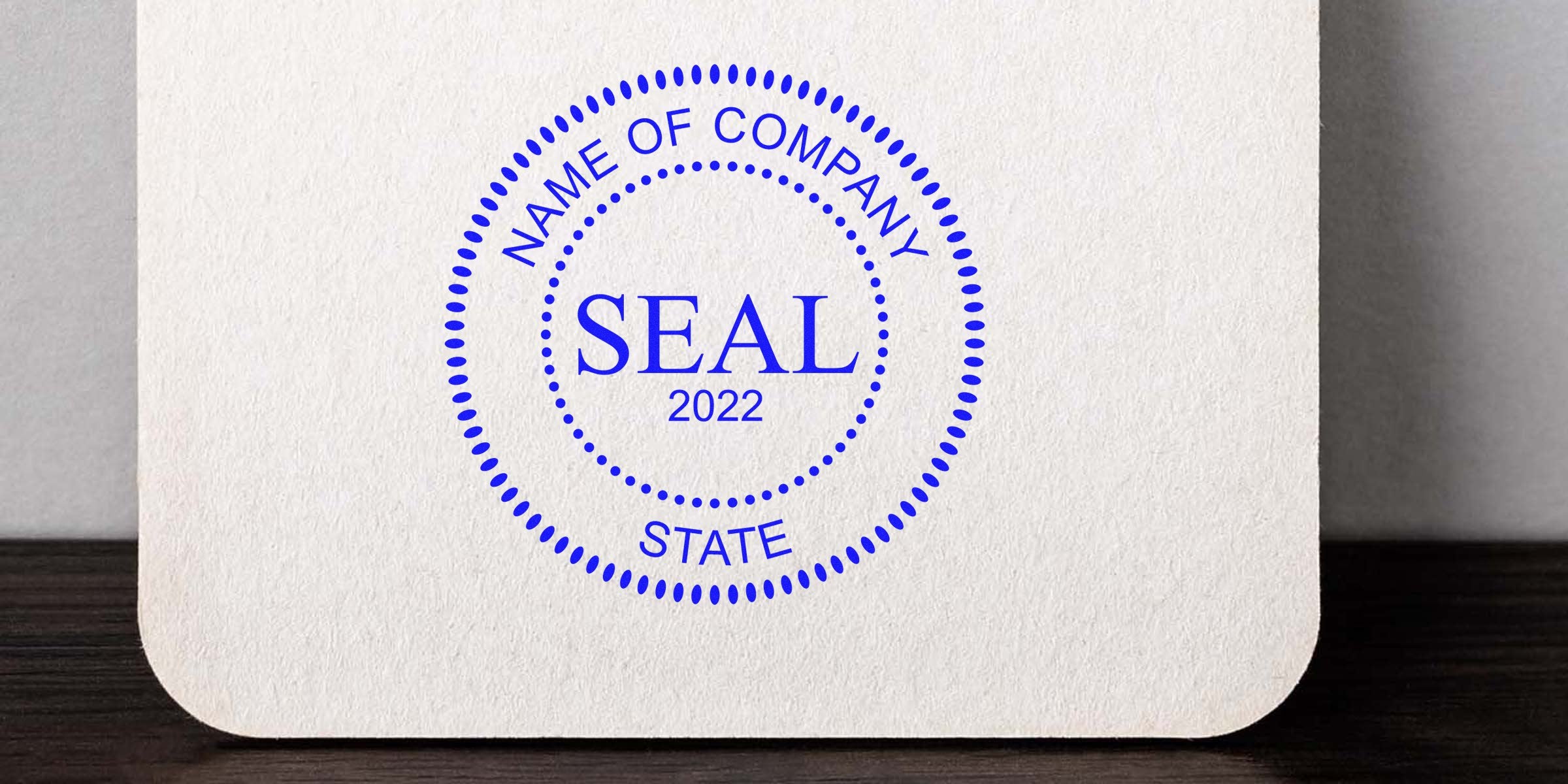 Blue circular seal with dotted border reading "NAME OF COMPANY SEAL 2022 STATE" on a textured card.