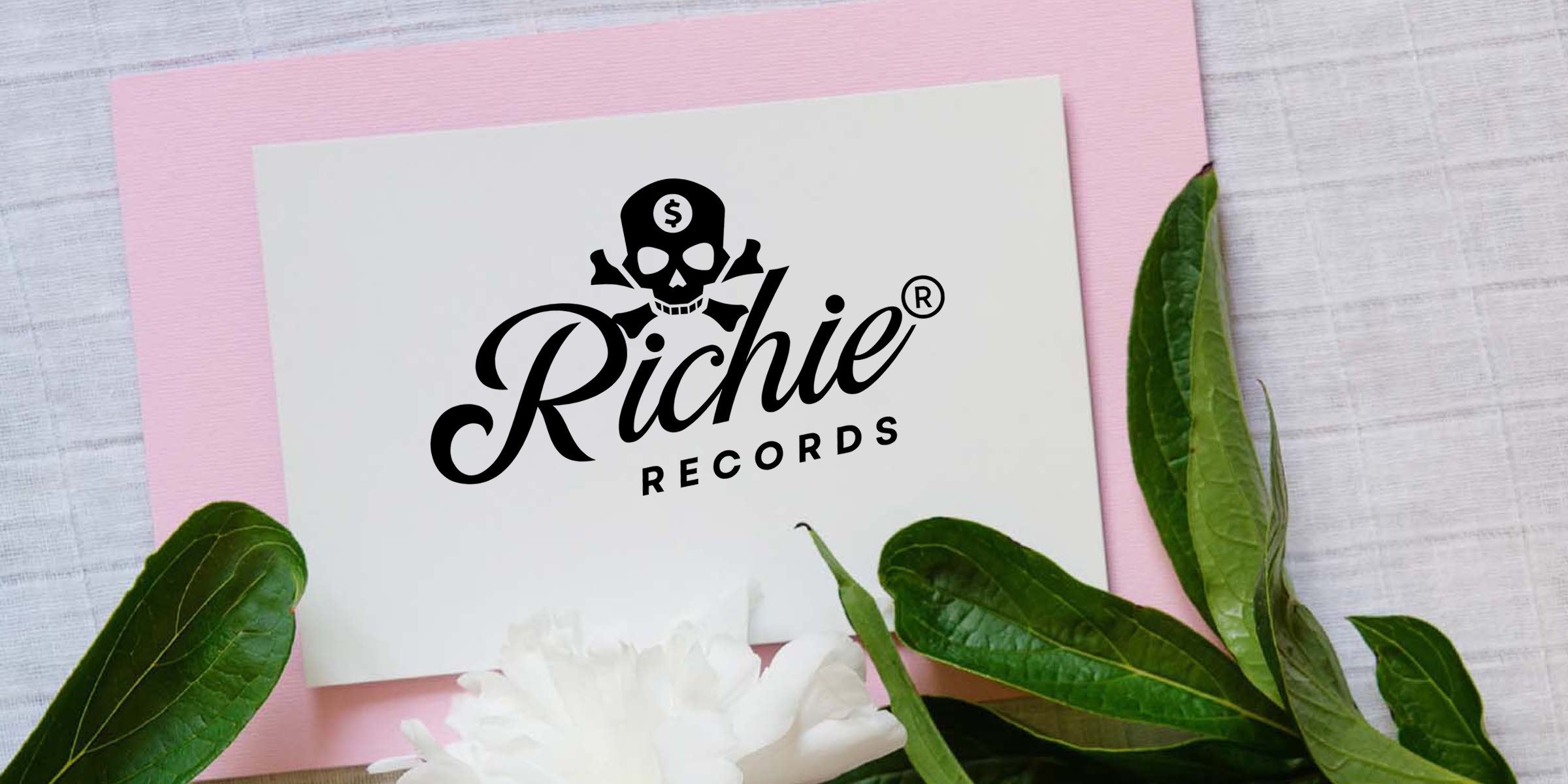 White card on pink paper with black "Richie Records" script logo featuring a skull with a dollar symbol and crossbones, surrounded by green leaves and a white flower.