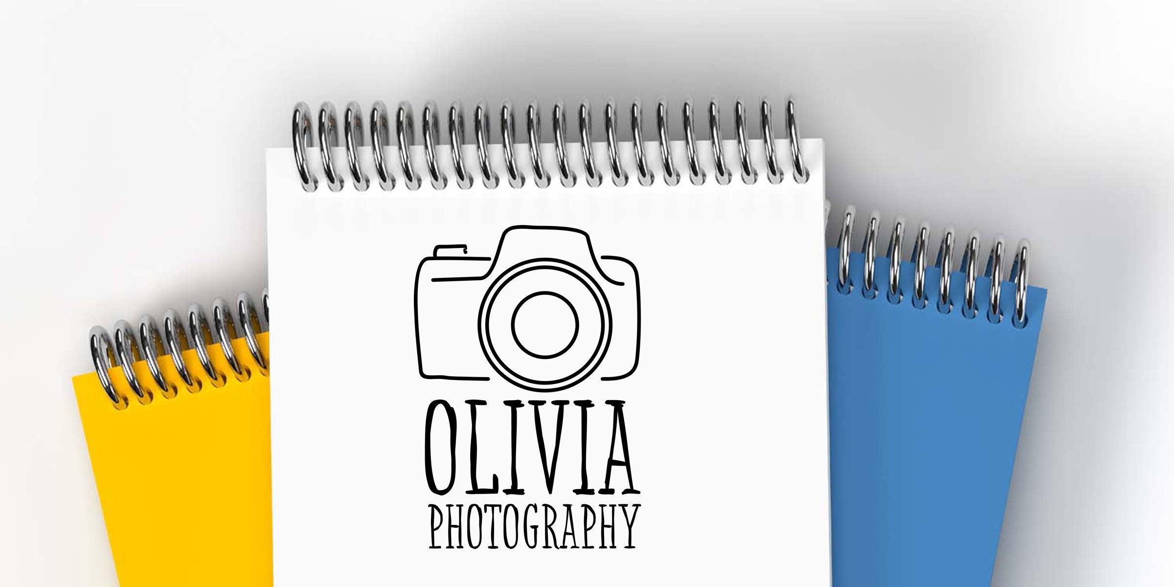 Spiral-bound notepad mockup with minimalist camera logo and "Olivia Photography" text on white cover, layered over yellow and blue notepads — photography branding and logo stationery mockup