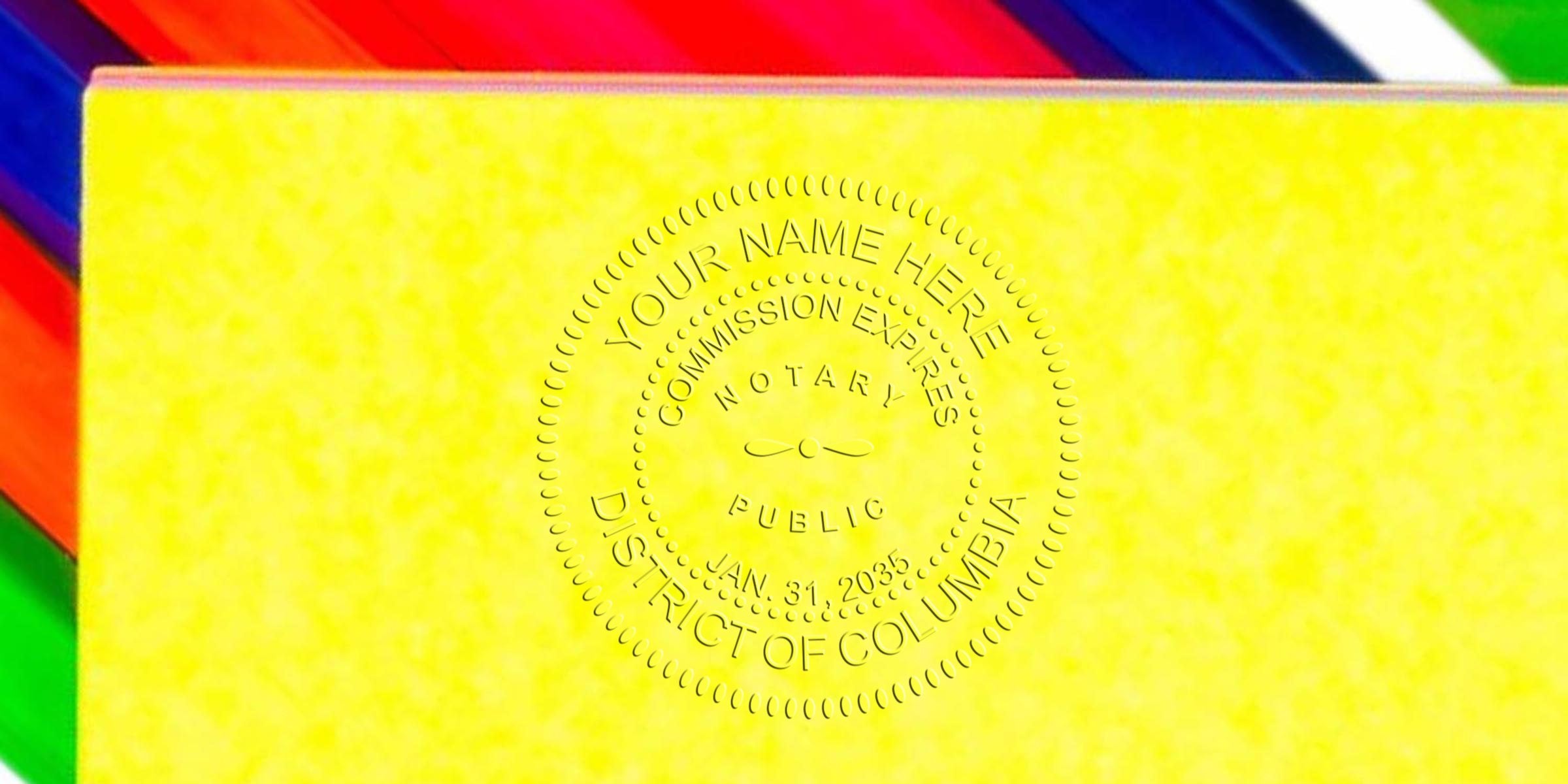 Embossed notary seal on bright yellow paper with colorful diagonal border, circular "Your Name Here" notary public seal reading "District of Columbia" and commission expiry date Jan. 31, 2035, close-up texture and detail.