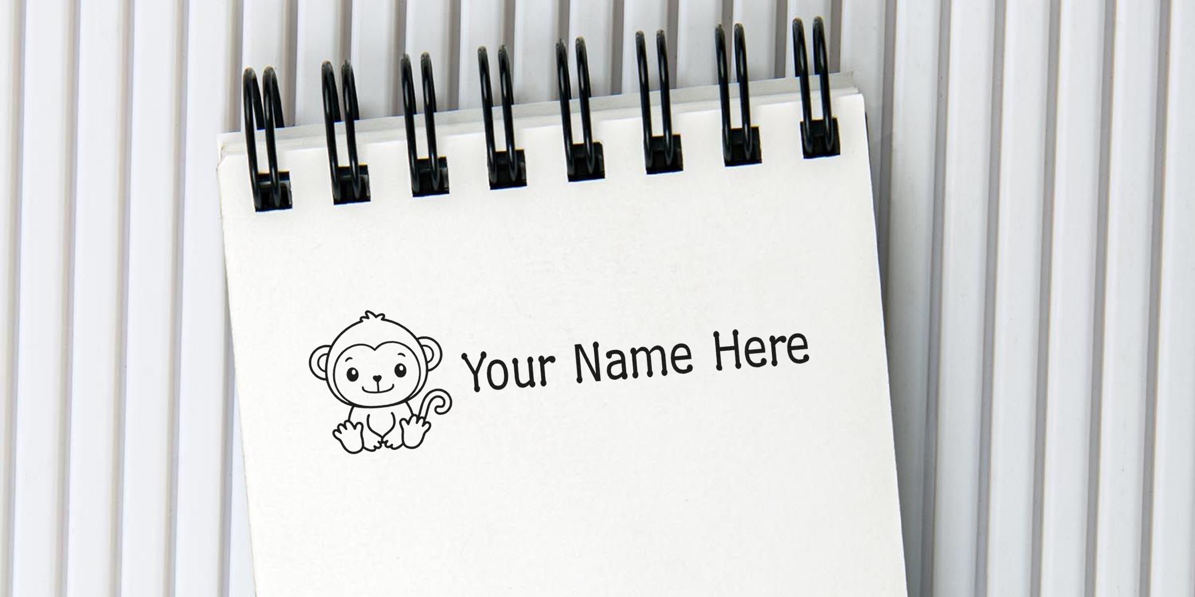 Spiral-bound notepad with the text “Your Name Here” and a cute cartoon monkey illustration.