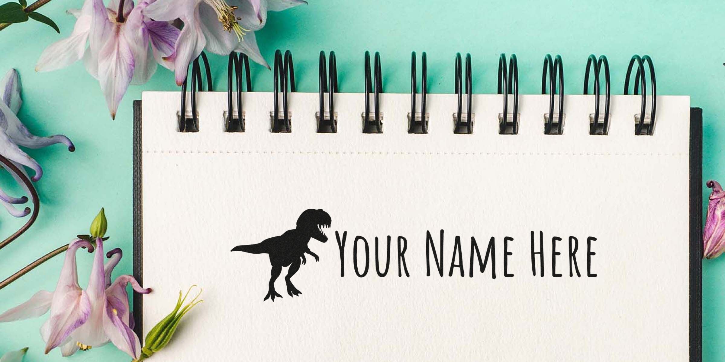 Spiral notebook page with a dinosaur silhouette and the words “Your Name Here,” set against a mint green background with pink flowers.