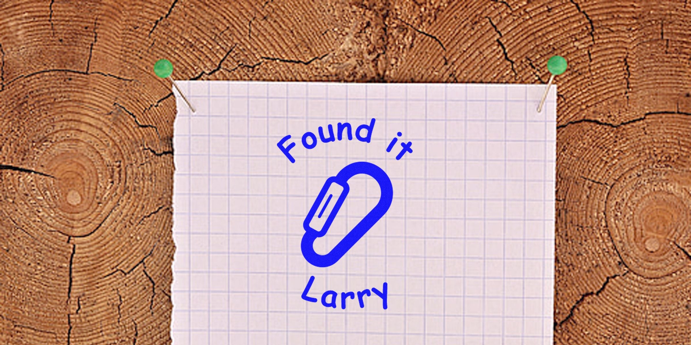 Note on grid paper showing a blue paperclip drawing with the words “Found it” and “Larry” against a wood background.