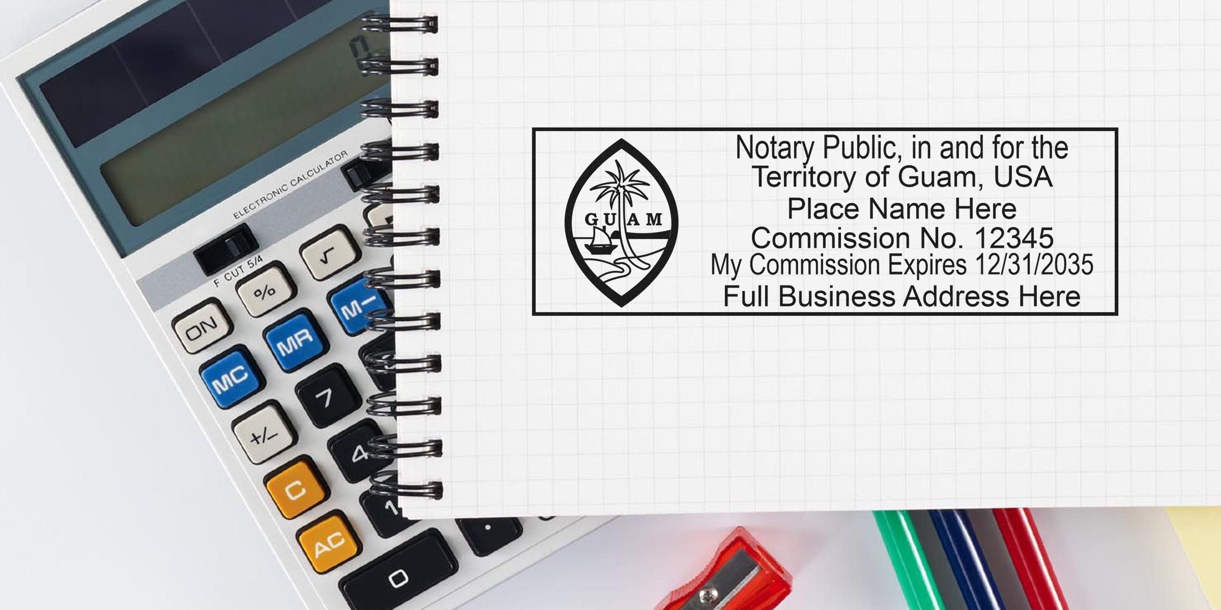 Overhead photo of a spiral notebook showing a Guam notary public rubber stamp imprint next to a calculator, colored pens and pencil sharpener, displaying commission number, expiration date and placeholder for full business address.