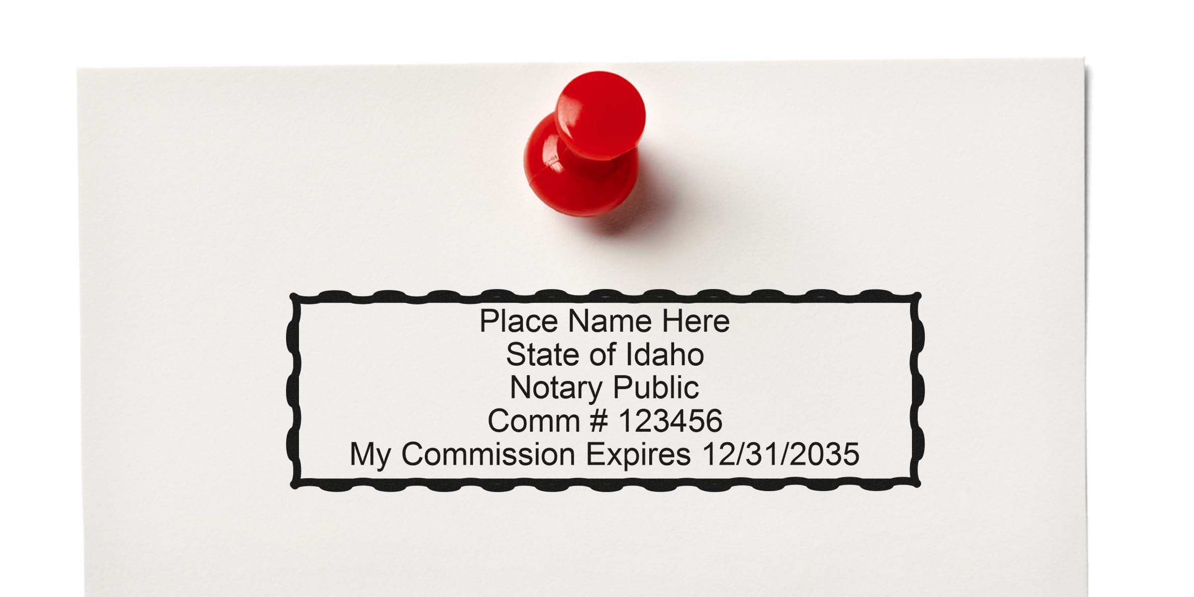 White paper pinned with a red pushpin showing a rectangular Idaho notary stamp template reading "Place Name Here, State of Idaho, Notary Public, Comm #123456, My Commission Expires 12/31/2035"