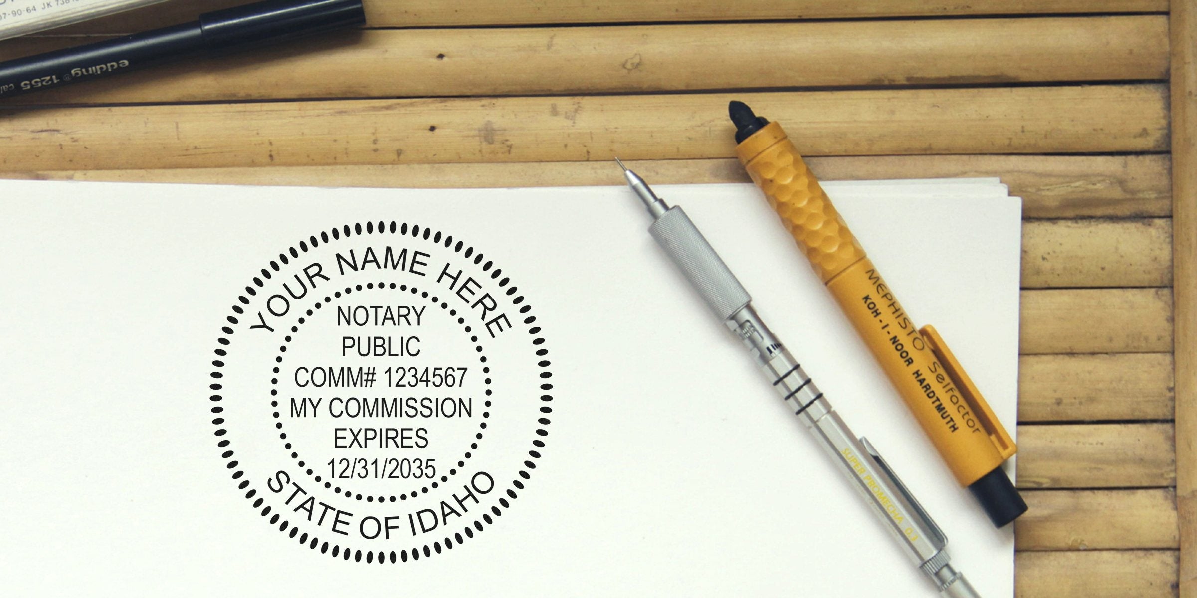 Notary public round stamp mockup reading "Your Name Here, State of Idaho" printed on white paper beside a mechanical pencil and yellow pen on a wooden desk