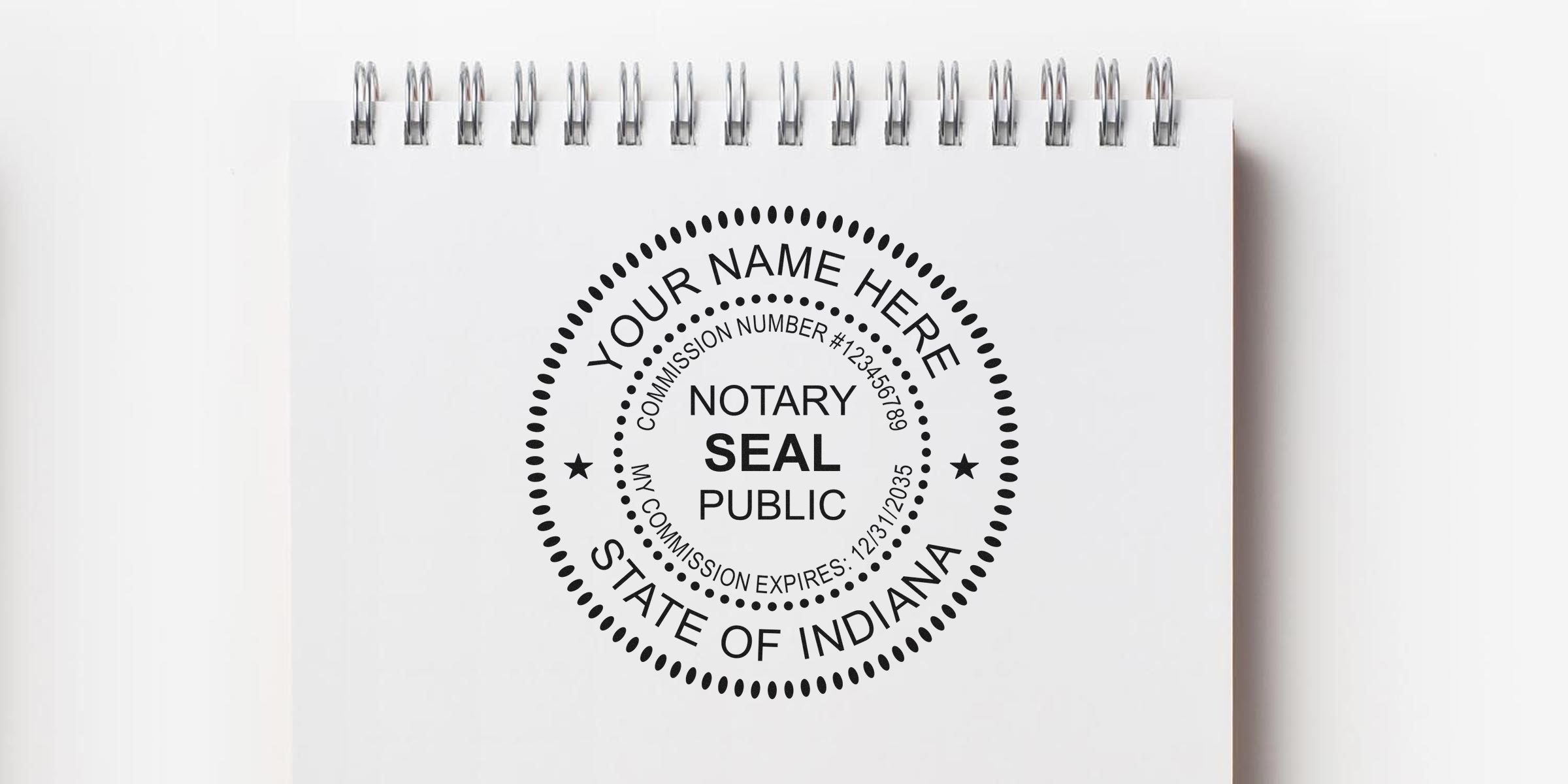Top-down photo of a spiral-bound notebook page featuring a black circular notary public seal mockup reading "Your Name Here," "State of Indiana," and commission details.