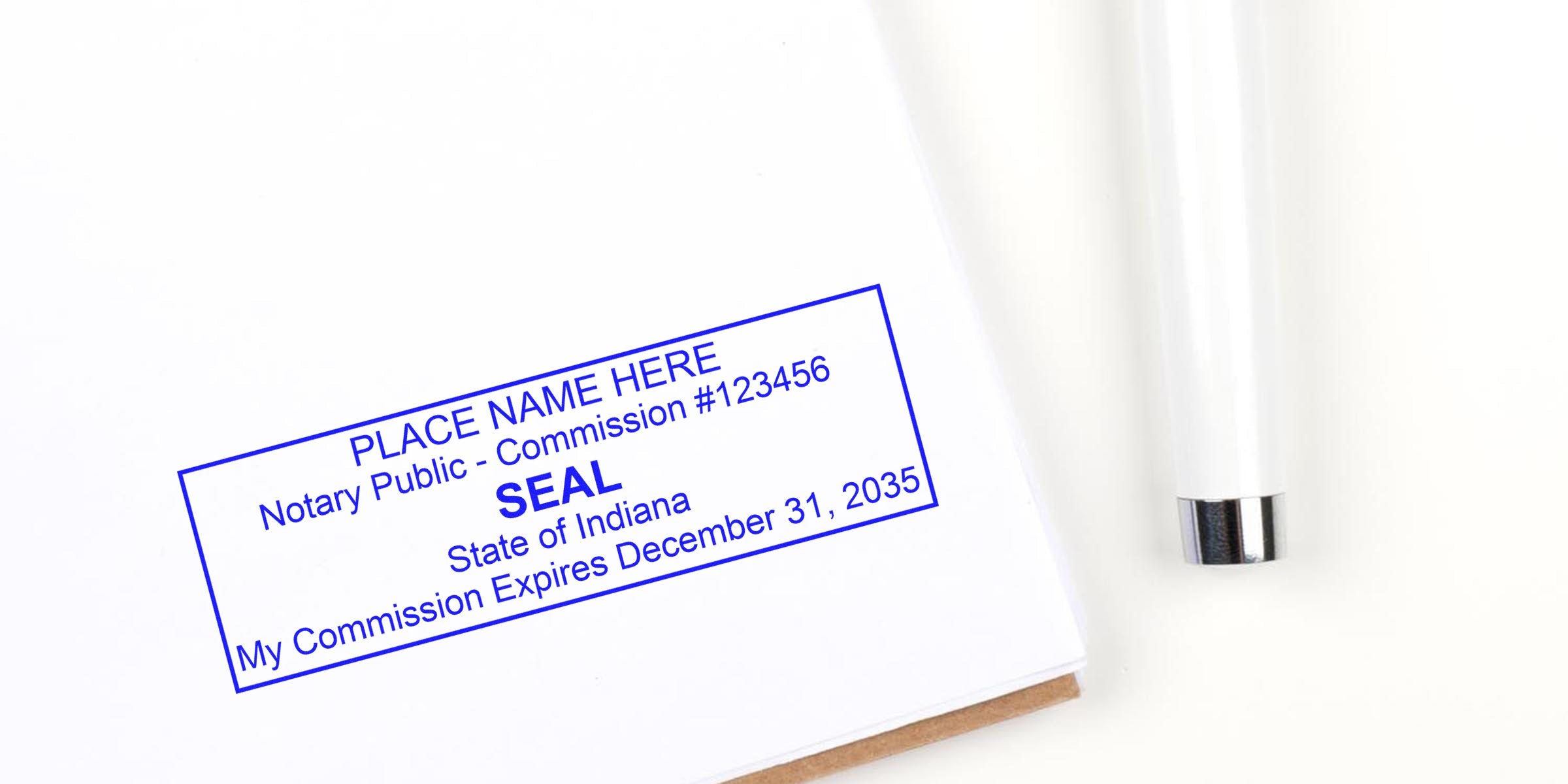 Blue rectangular notary seal stamp on white paper reading "PLACE NAME HERE, Notary Public - Commission #123456, SEAL, State of Indiana, My Commission Expires December 31, 2035" with a white pen nearby