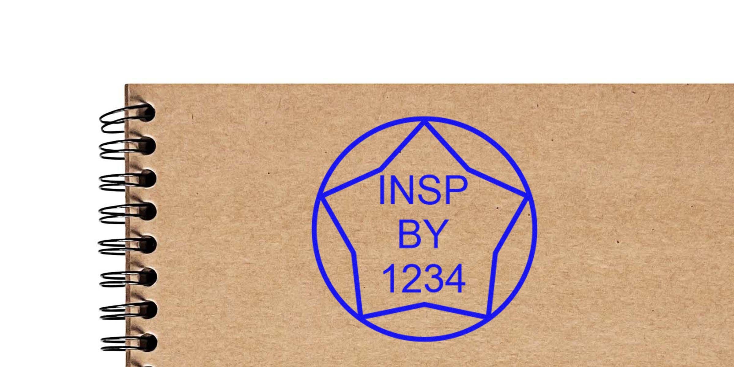 Blue circular emblem with a pentagonal star outline and the text “INSP BY 1234” in blue on a brown notebook cover.