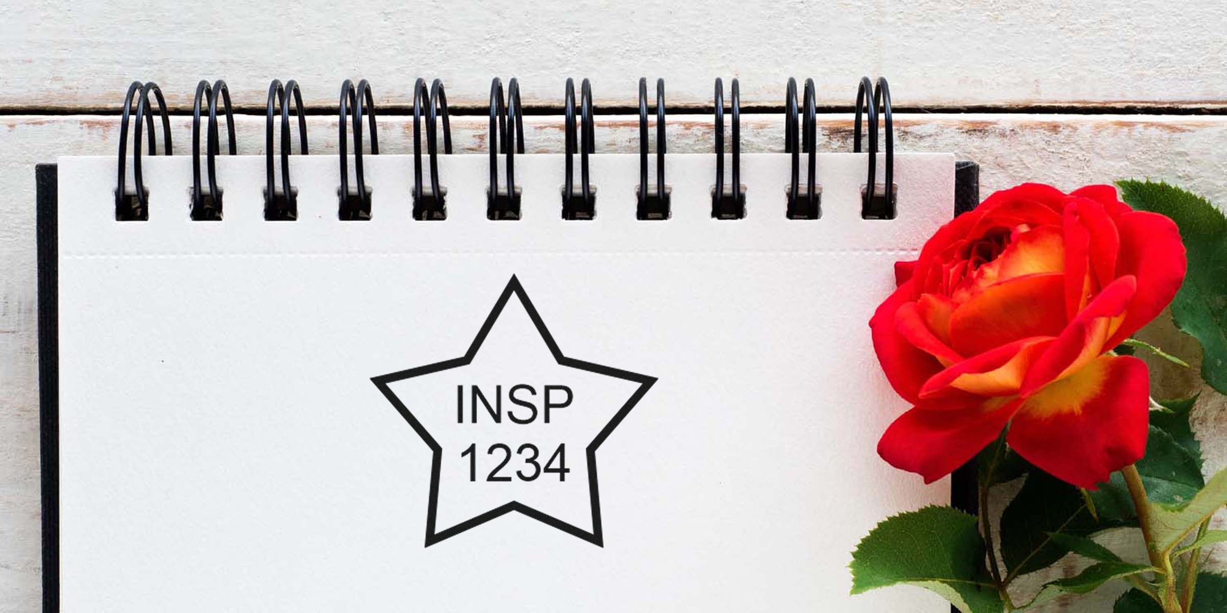 Notebook page with a black star outline and the text INSP 1234, beside a red rose.