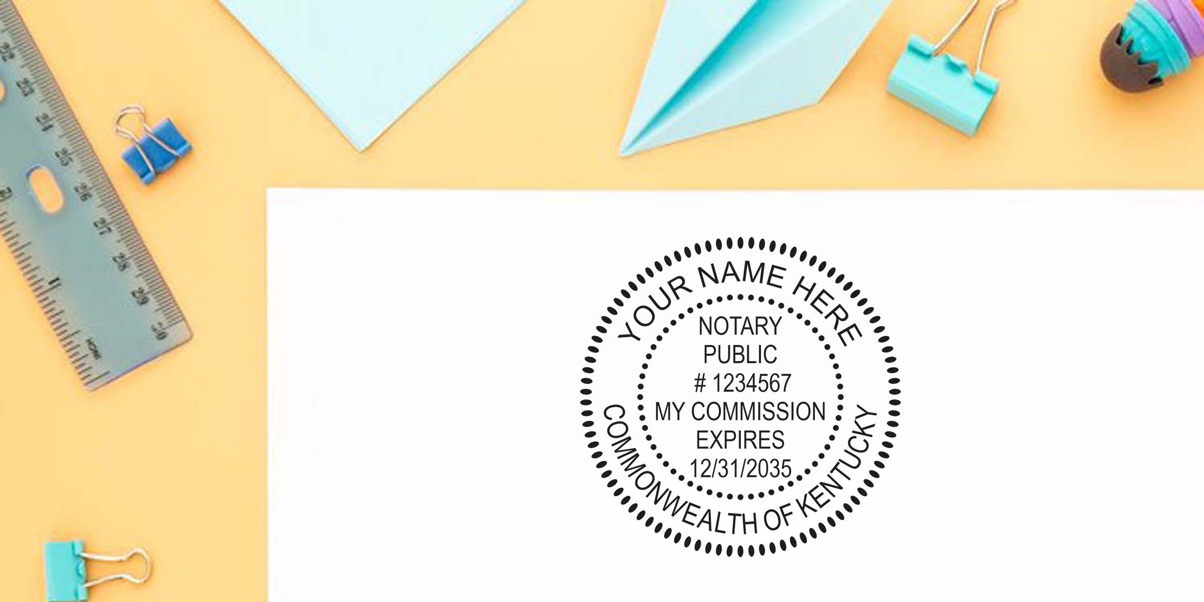 Mockup of a circular Notary Public stamp reading "Commonwealth of Kentucky" on white paper on a pastel yellow desk with ruler, paper airplane and binder clips.