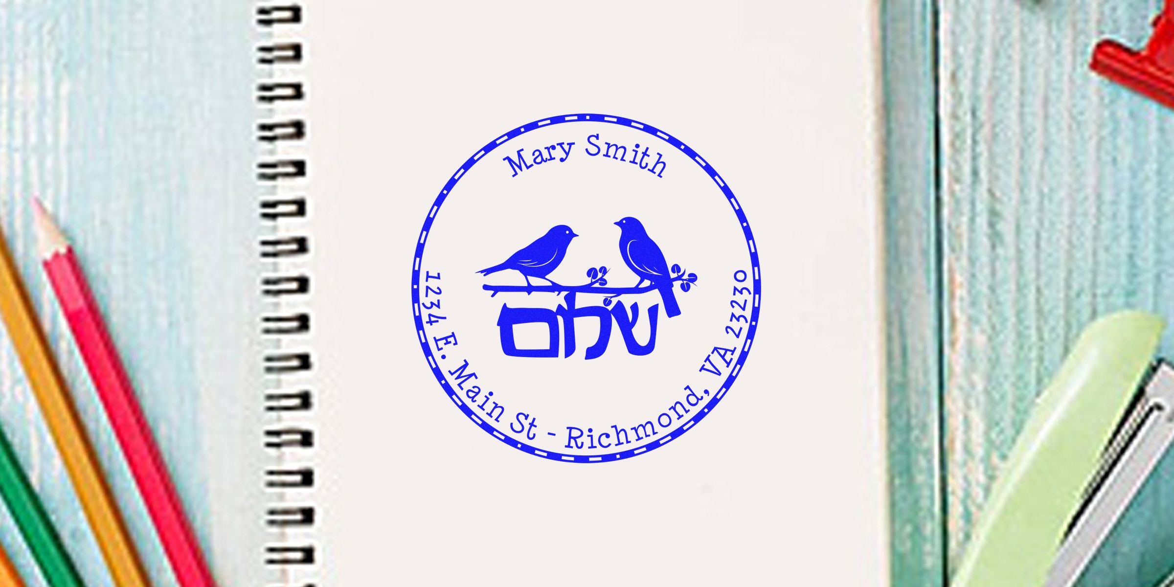Blue circular stamp with two birds, the name Mary Smith, and the address 1234 E. Main St., Richmond, VA 23230, on a notebook page.