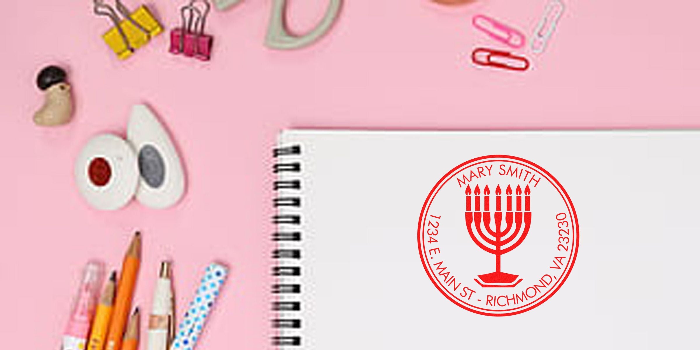 Notebook with a red circular seal reading “Mary Smith” and an address, placed on a pink background.