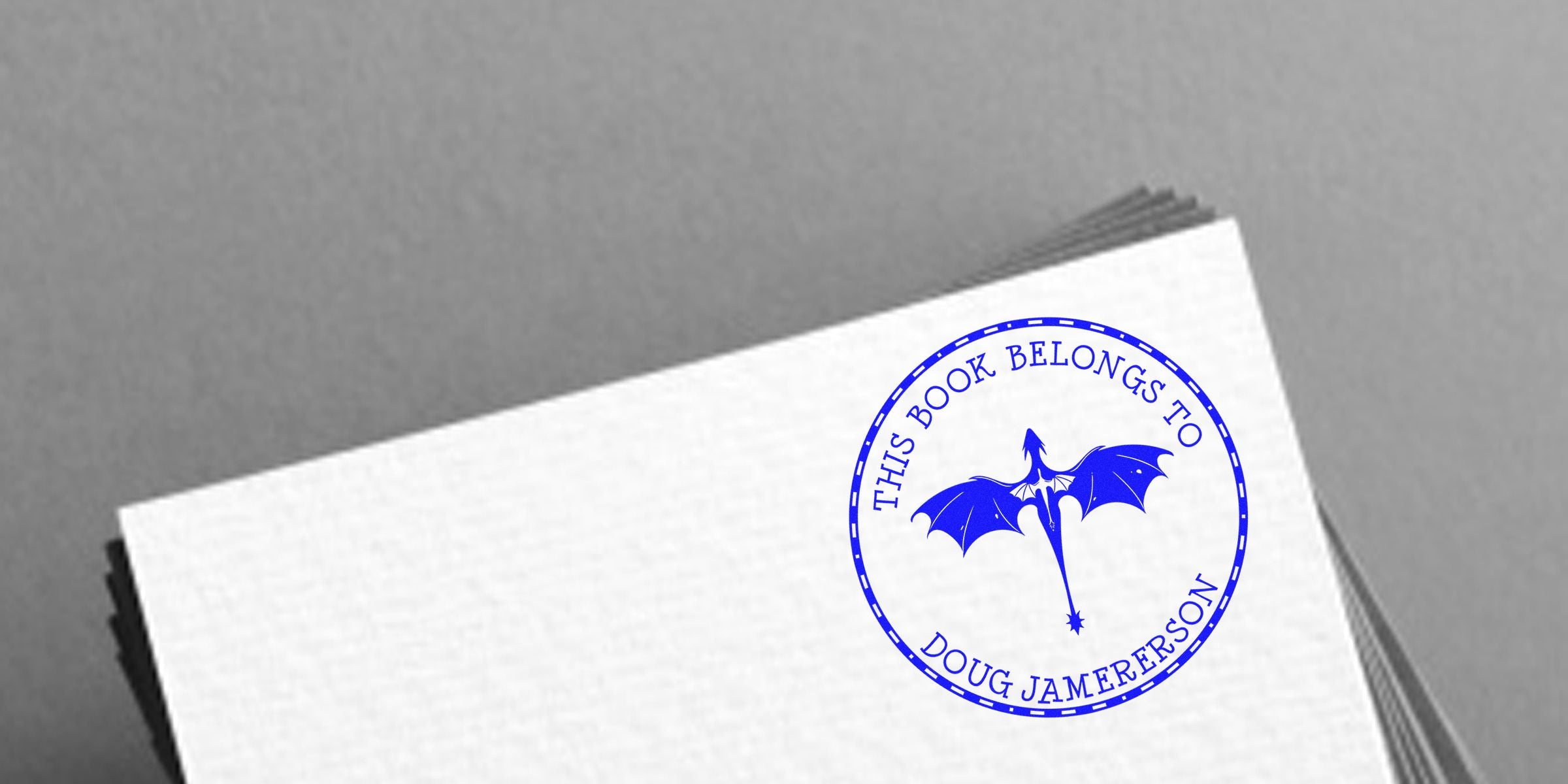 Blue circular stamp reading “THIS BOOK BELONGS TO DOUG JAMERSON” with a blue dragon motif on a white page.