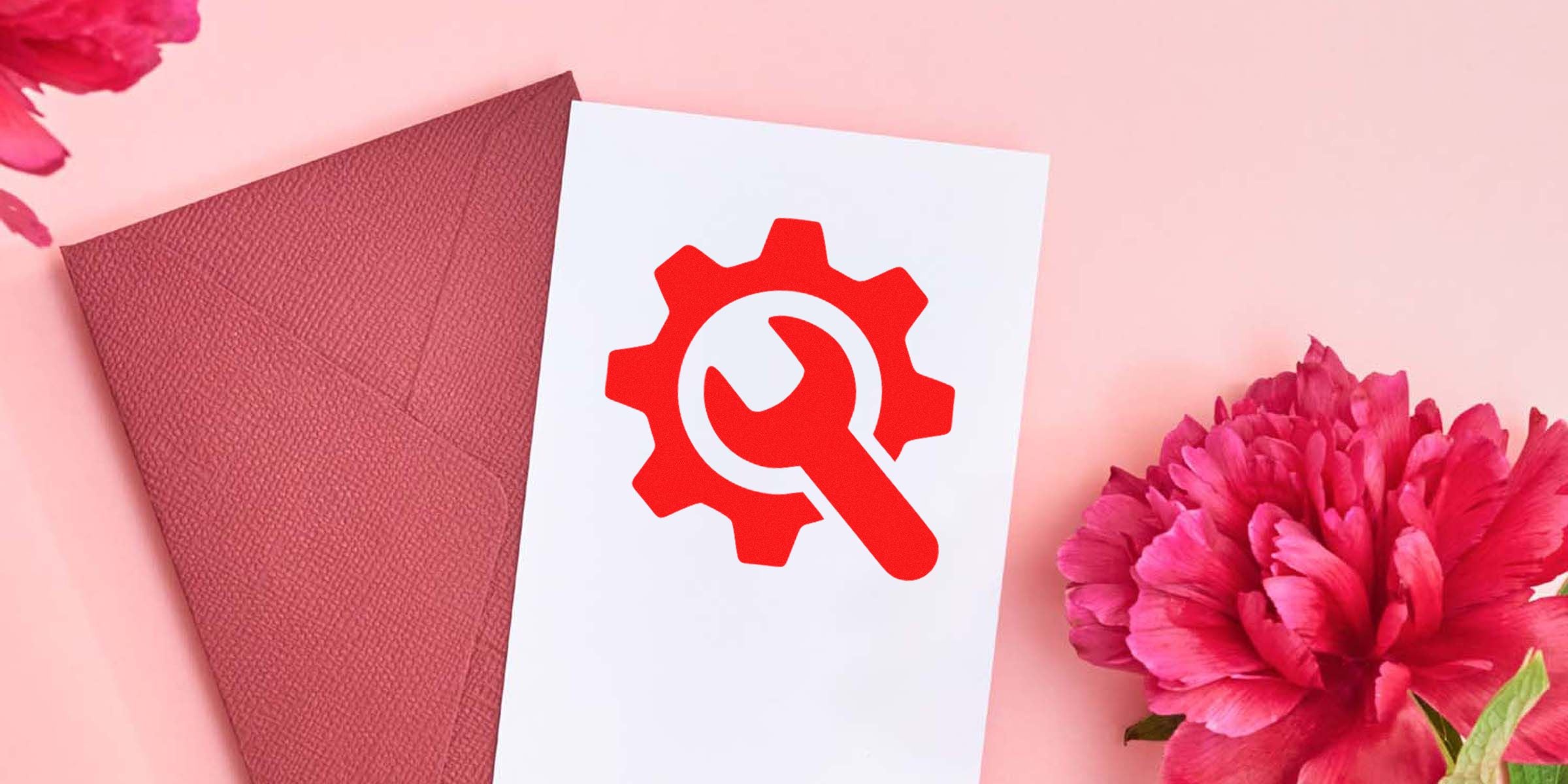 White card displaying a red gear with a wrench icon on a pink background, next to a pink envelope and pink flowers.