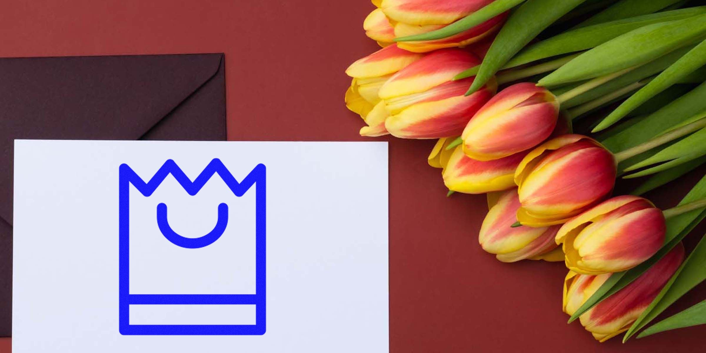 Blue outline gift bag icon on a white card beside a bouquet of yellow and red tulips.