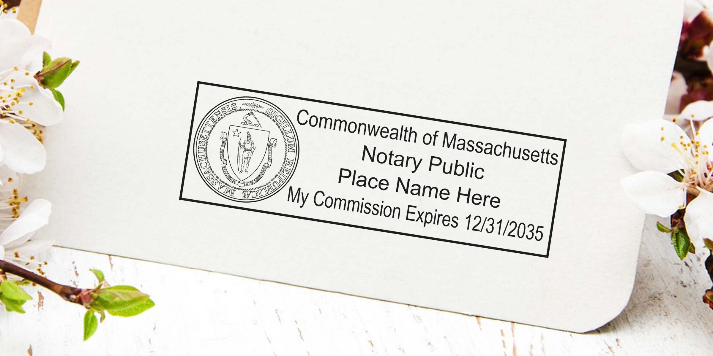 Notary public stamp on cream paper featuring the Massachusetts state seal, placeholder "Place Name Here" and commission expiry date 12/31/2035, photographed with white blossom flowers and rustic wooden background