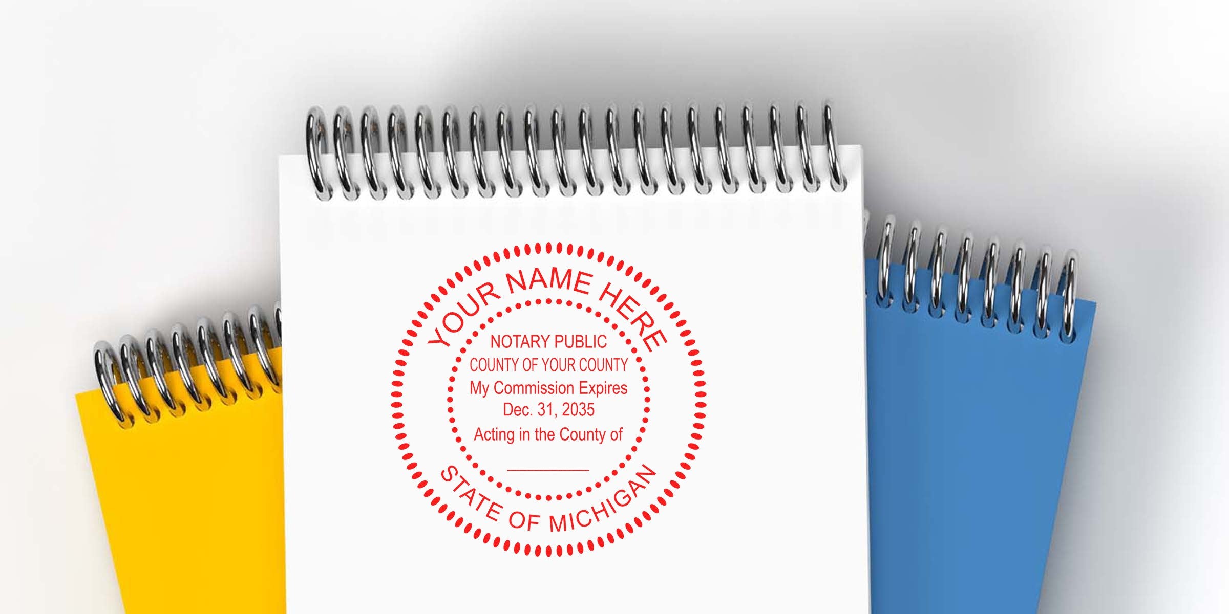 Top-down photo of spiral-bound notebooks in white, yellow, and blue; white cover features a red circular Michigan notary stamp mockup reading "Your Name Here, Notary Public, State of Michigan."