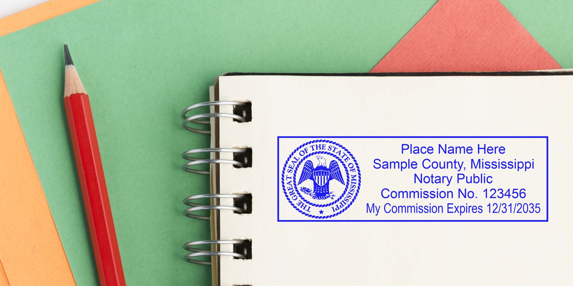 Blue Mississippi notary public stamp impression on spiral notebook page, with red pencil and layered green, orange and coral paper background
