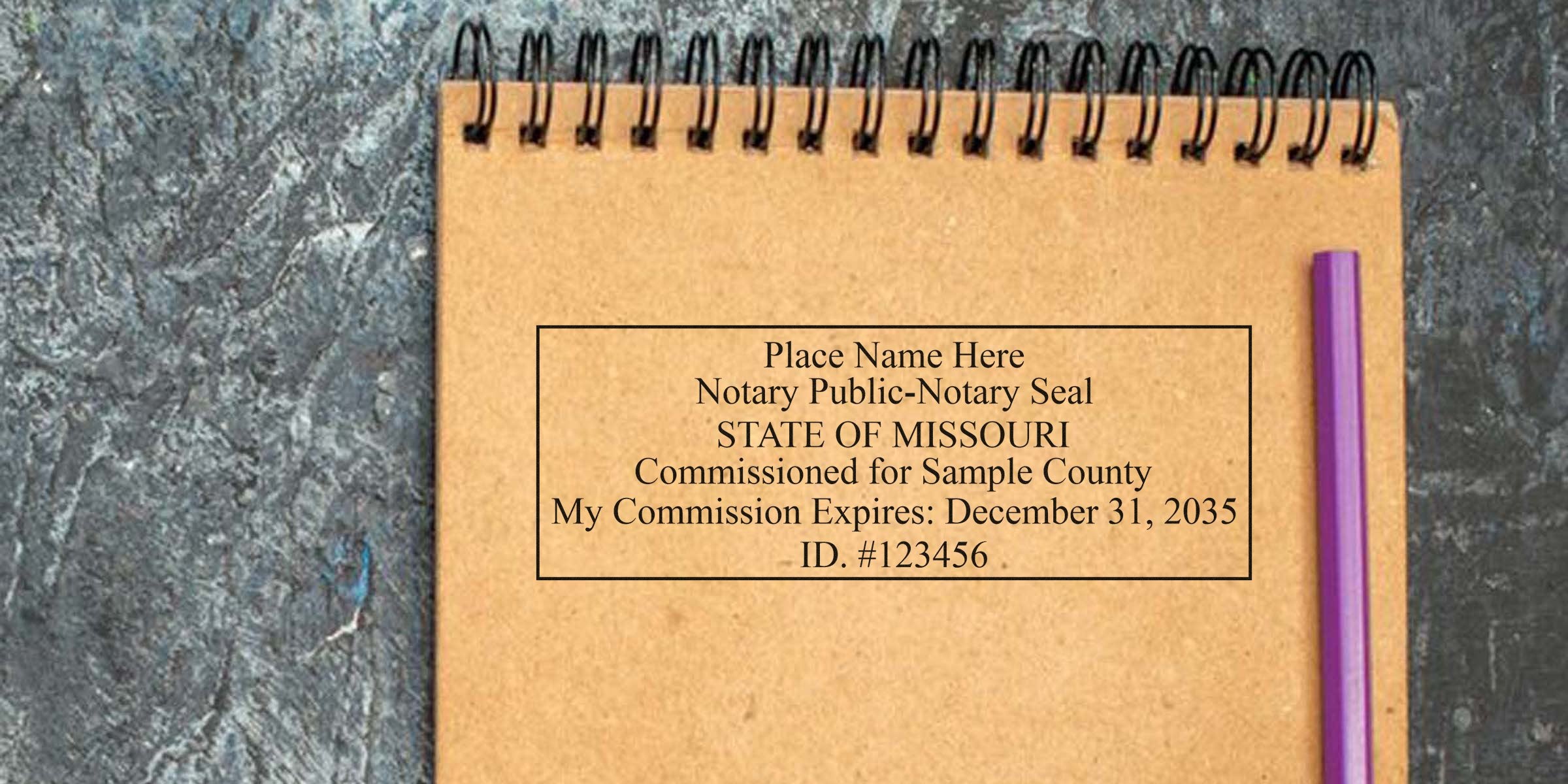 Spiral kraft notebook showing a sample Missouri notary public seal and commission details, with a purple pencil on a dark textured background