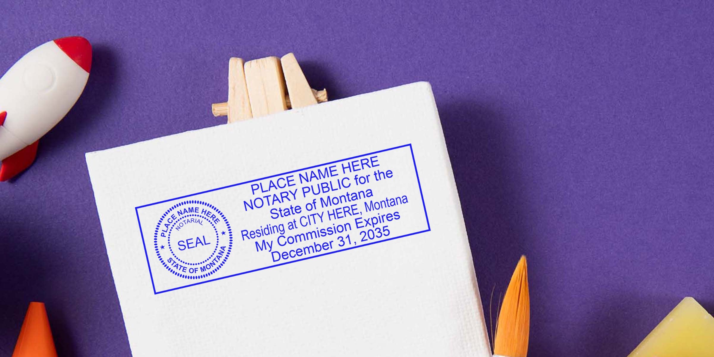 Blue notary stamp template on white canvas showing circular "SEAL" emblem and rectangular text reading "PLACE NAME HERE NOTARY PUBLIC for the State of Montana… My Commission Expires December 31, 2035," on purple background with paintbrush and toy rocket.