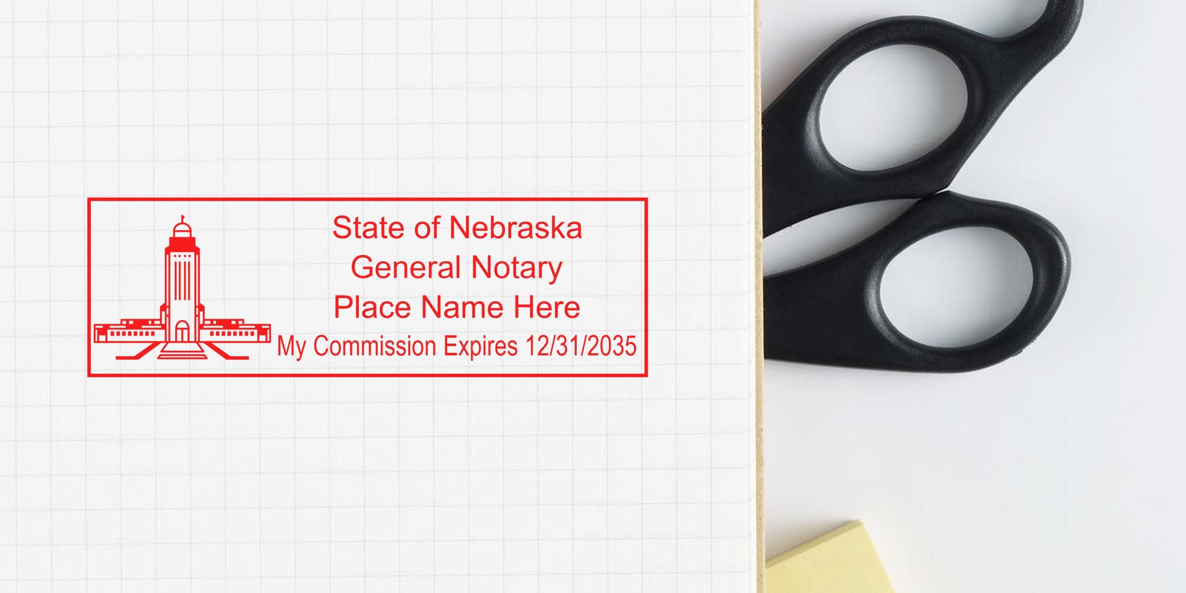 Red State of Nebraska general notary stamp mockup on grid paper with placeholder name and commission expiration date 12/31/2035, photographed beside black scissors and a yellow sticky note.