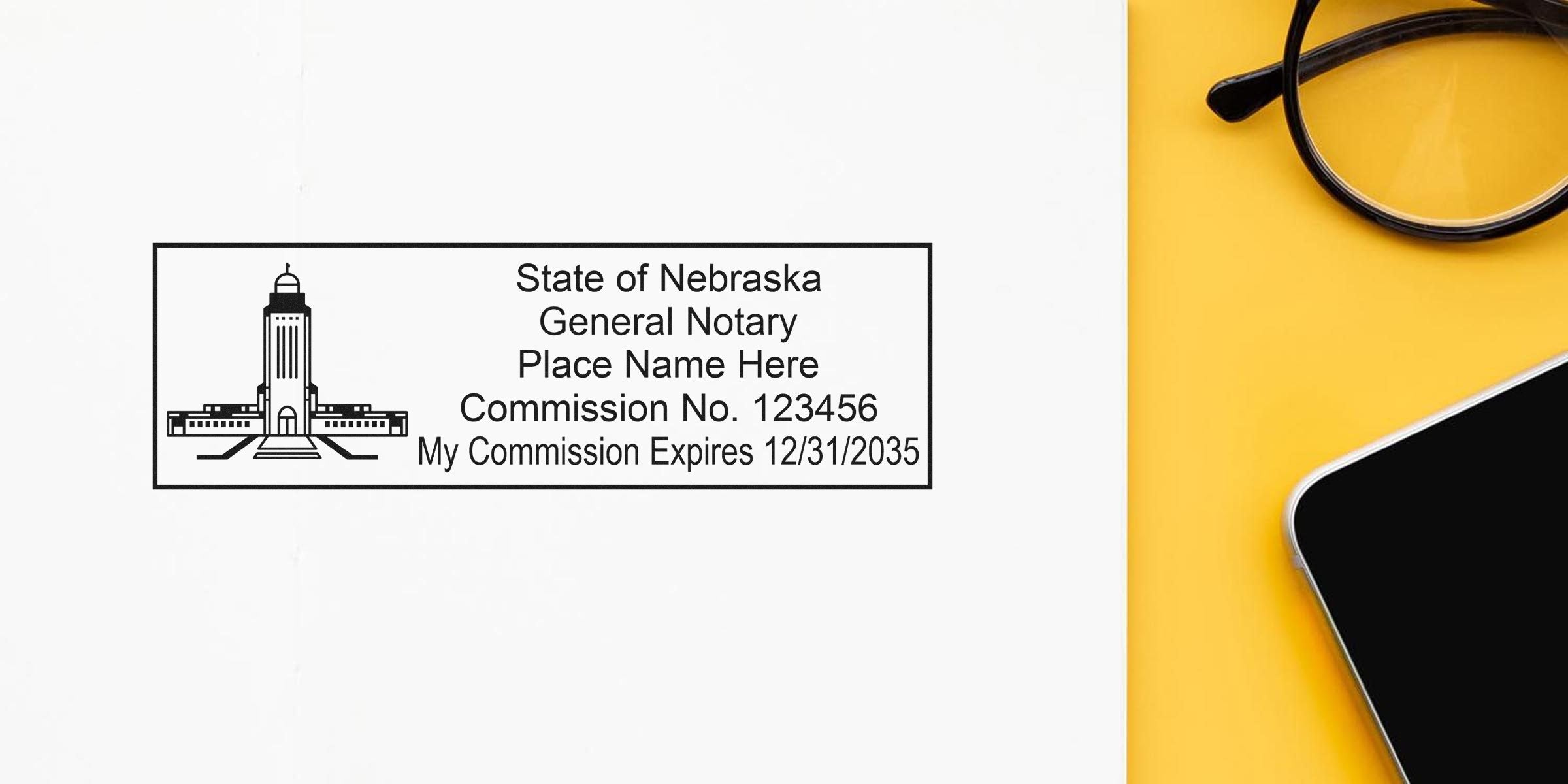 Nebraska notary stamp sample showing a rectangular notary seal with capitol building icon, placeholder name, commission no. 123456 and expiration 12/31/2035 on white paper beside glasses and smartphone on yellow background