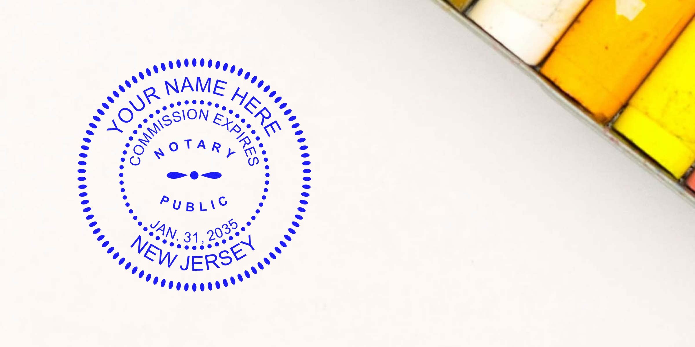 Blue circular notary public stamp reading "NEW JERSEY" on white paper with customizable name and expiration date, colored pastel chalks in the top-right corner