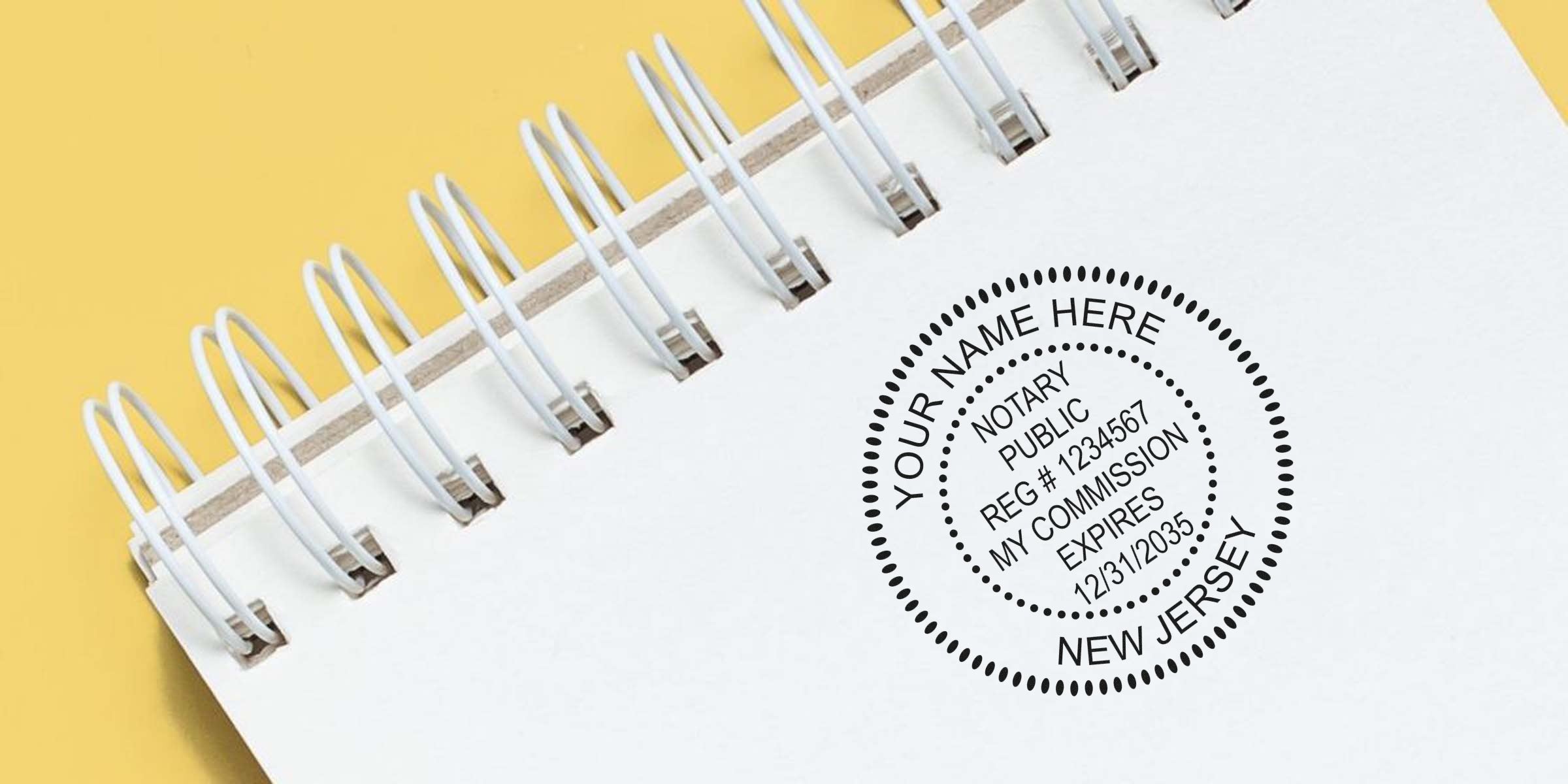 Close-up of a white spiral-bound notebook on a yellow background featuring a black circular notary public stamp reading "Your Name Here," registration number, commission expiry date and "New Jersey."