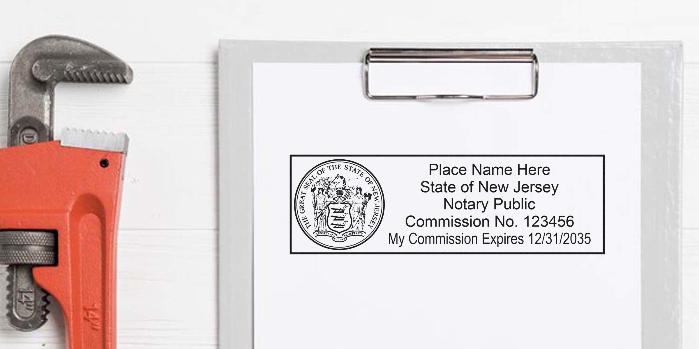 Blank New Jersey notary stamp sample on clipboard showing state seal, commission number and expiration date, placed beside a red pipe wrench on white wooden background