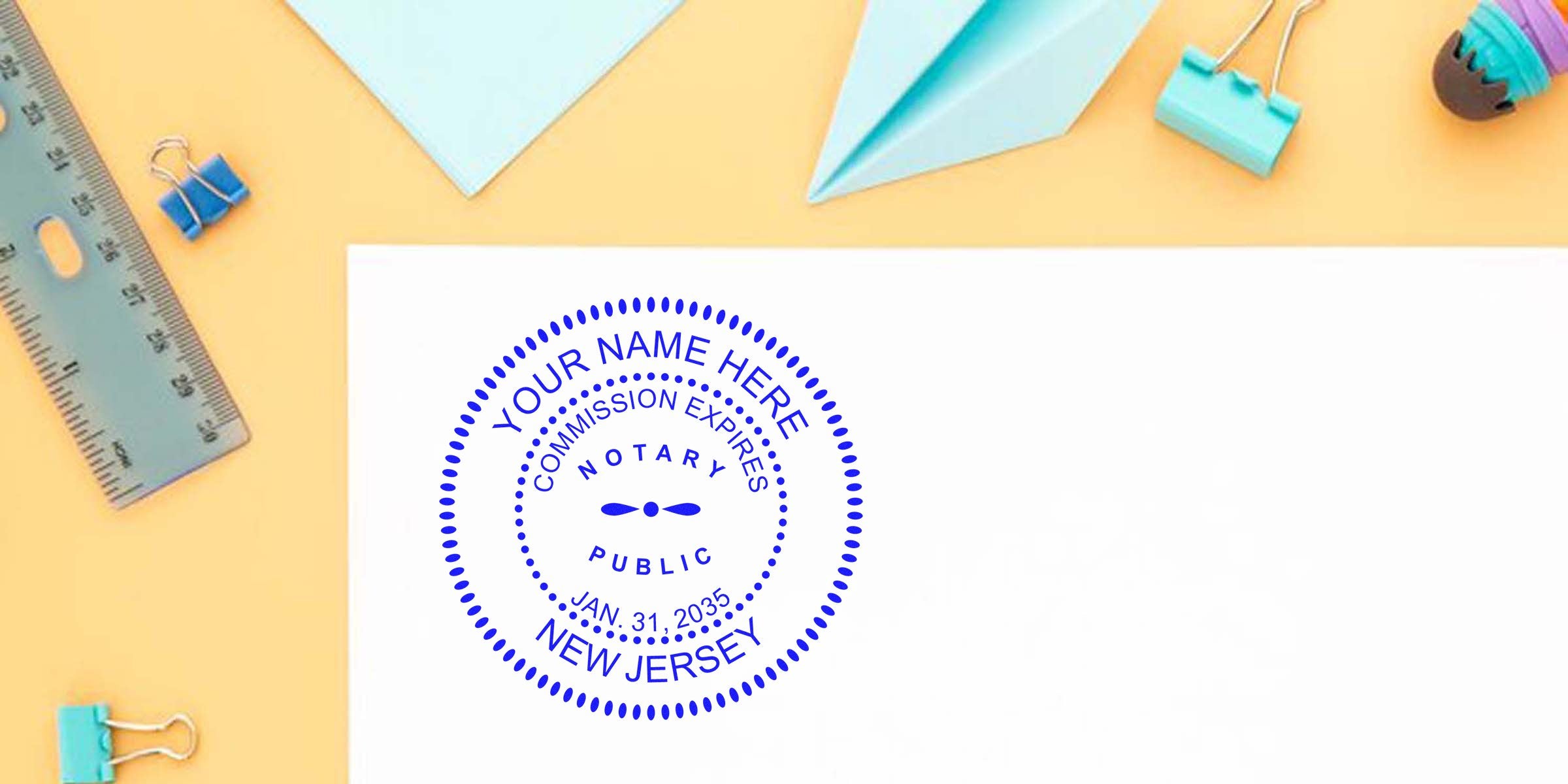 Blue circular Notary Public stamp reading "Your Name Here, Commission Expires Jan. 31, 2035, New Jersey" on white paper with pastel desk supplies