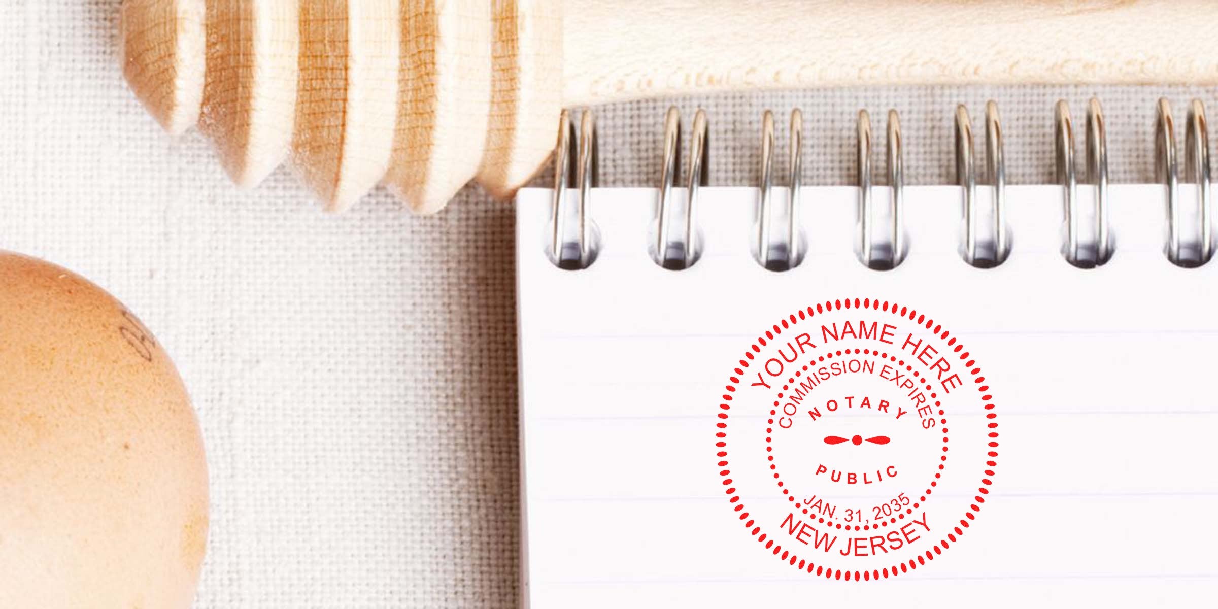 Spiral notebook with lined pages stamped with red "Notary Public New Jersey" seal, wooden honey dipper and brown egg on textured linen background, close-up office stationery photo