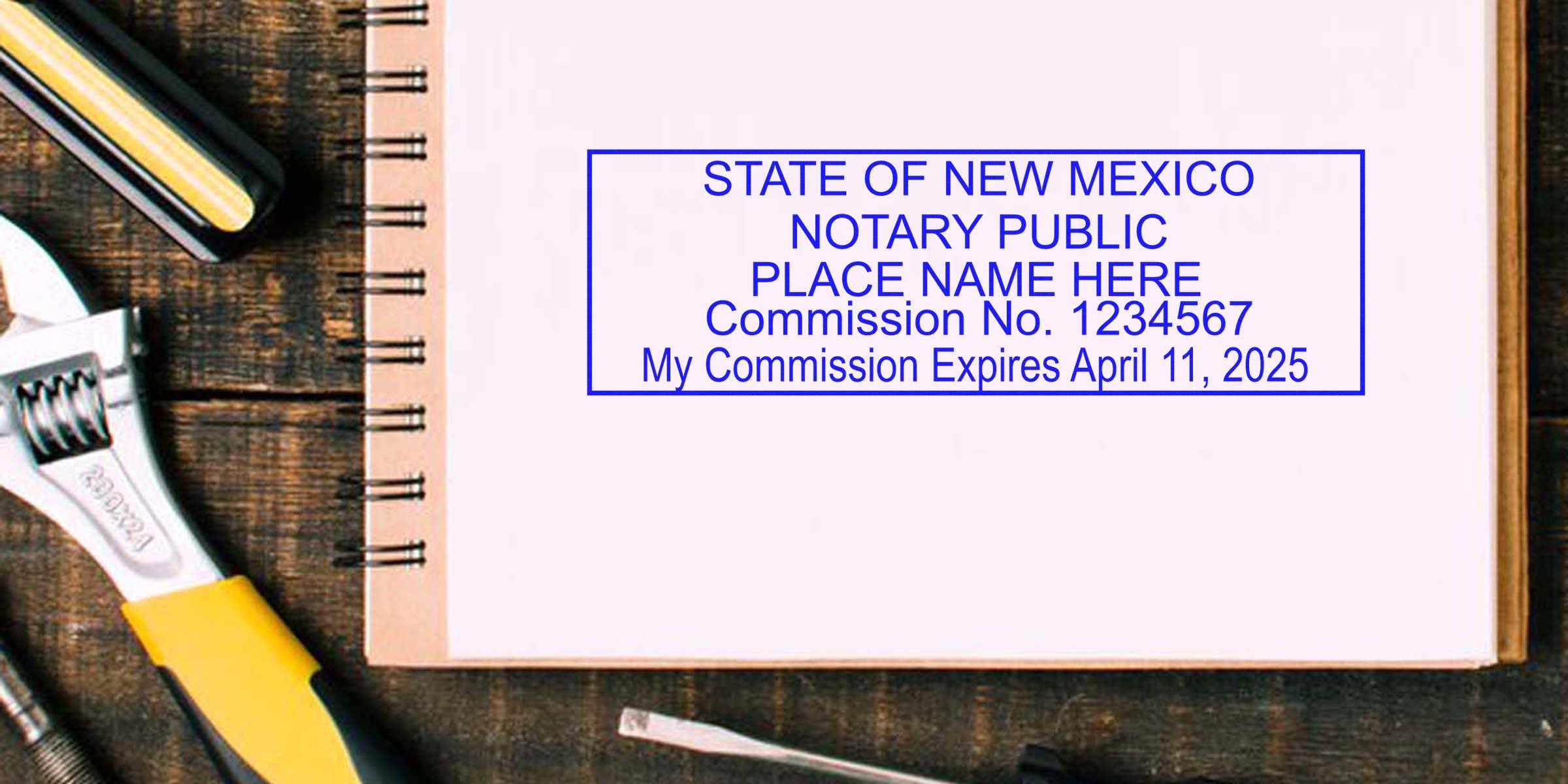 Blue "State of New Mexico Notary Public" stamp on open spiral notebook beside wrench and tools, close-up office/workbench scene