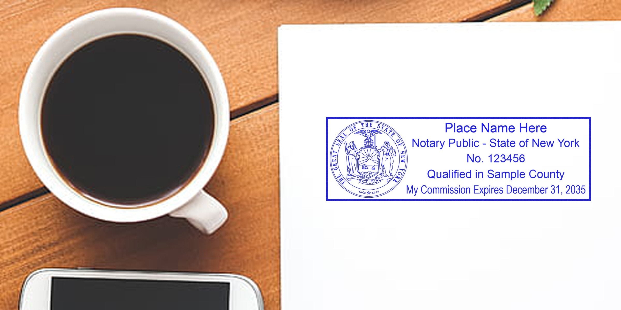 Top-down photo of a coffee cup, smartphone and a New York notary public stamp on white paper showing state seal, commission number and expiration date, arranged on a wooden desk — business office flat lay.