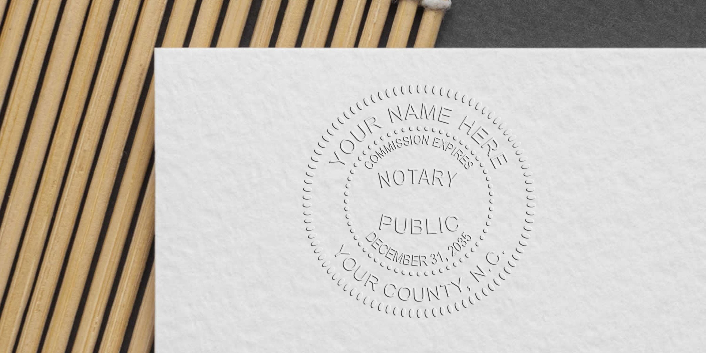 Close-up of an embossed notary public seal on textured white paper beside a bamboo mat, showing circular stamp details and date text
