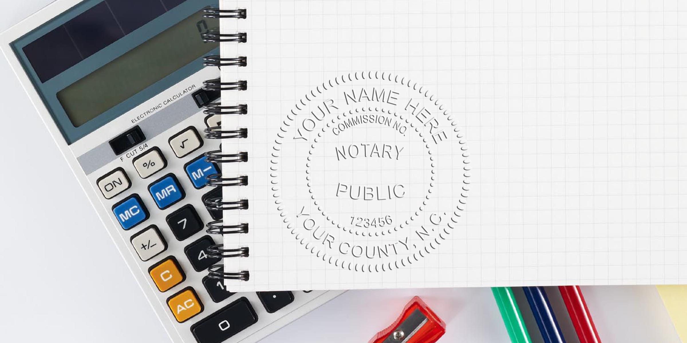 Spiral notebook with embossed "Notary Public" seal next to a calculator, colored pens and red pencil sharpener on a white desk — office supplies and notarization concept for legal, accounting, and administrative services
