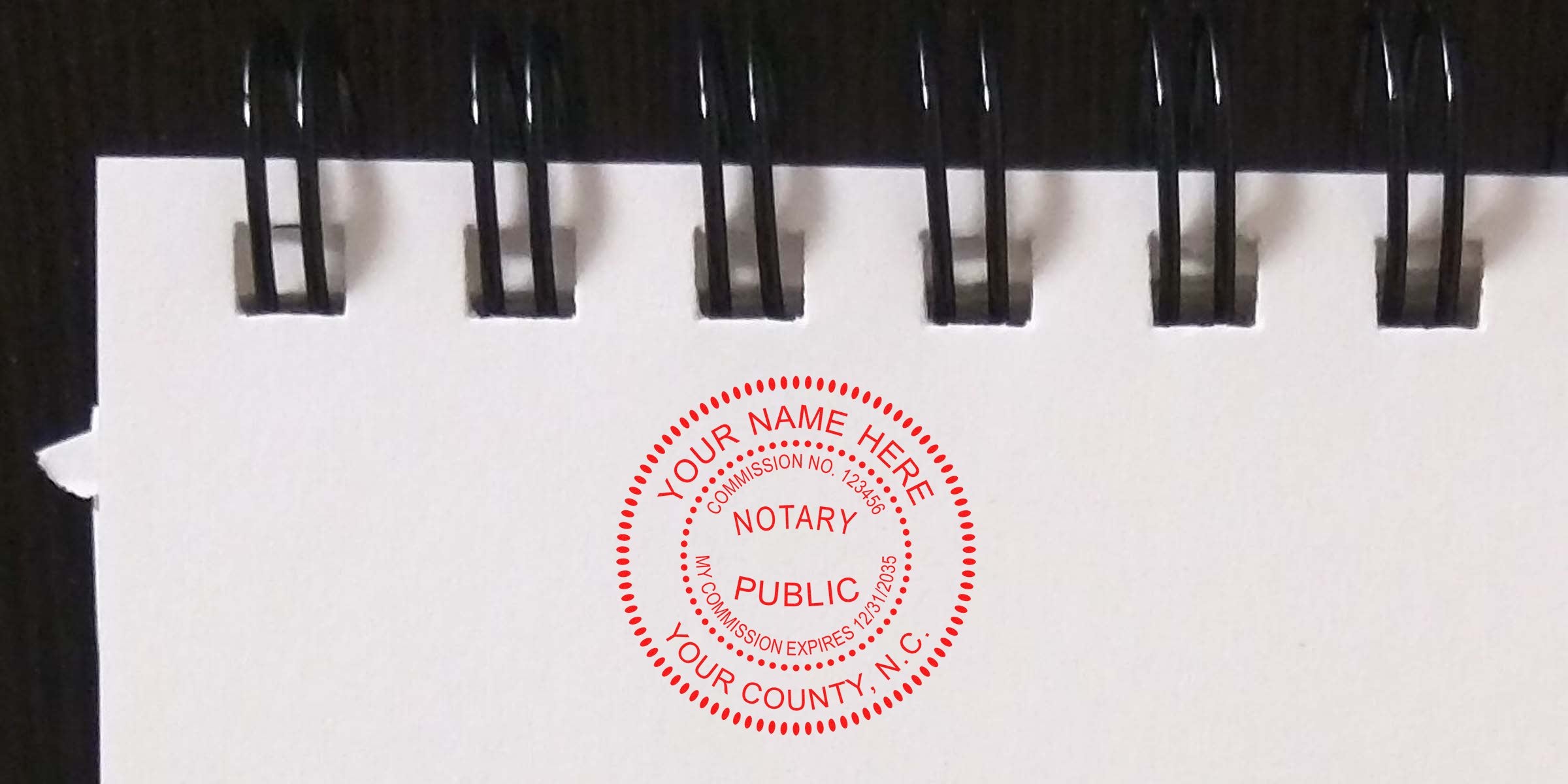 Red circular notary public stamp on blank white spiral-bound notebook page, close-up of notary seal and black coil binding