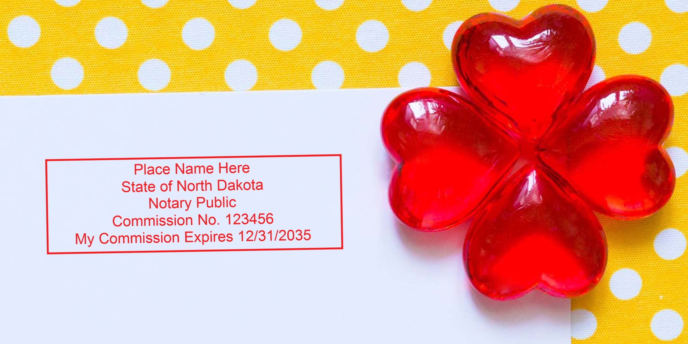 Notary stamp mockup on white paper reading "State of North Dakota Notary Public Commission No. 123456" beside red heart-shaped glass decoration on yellow polka dot background